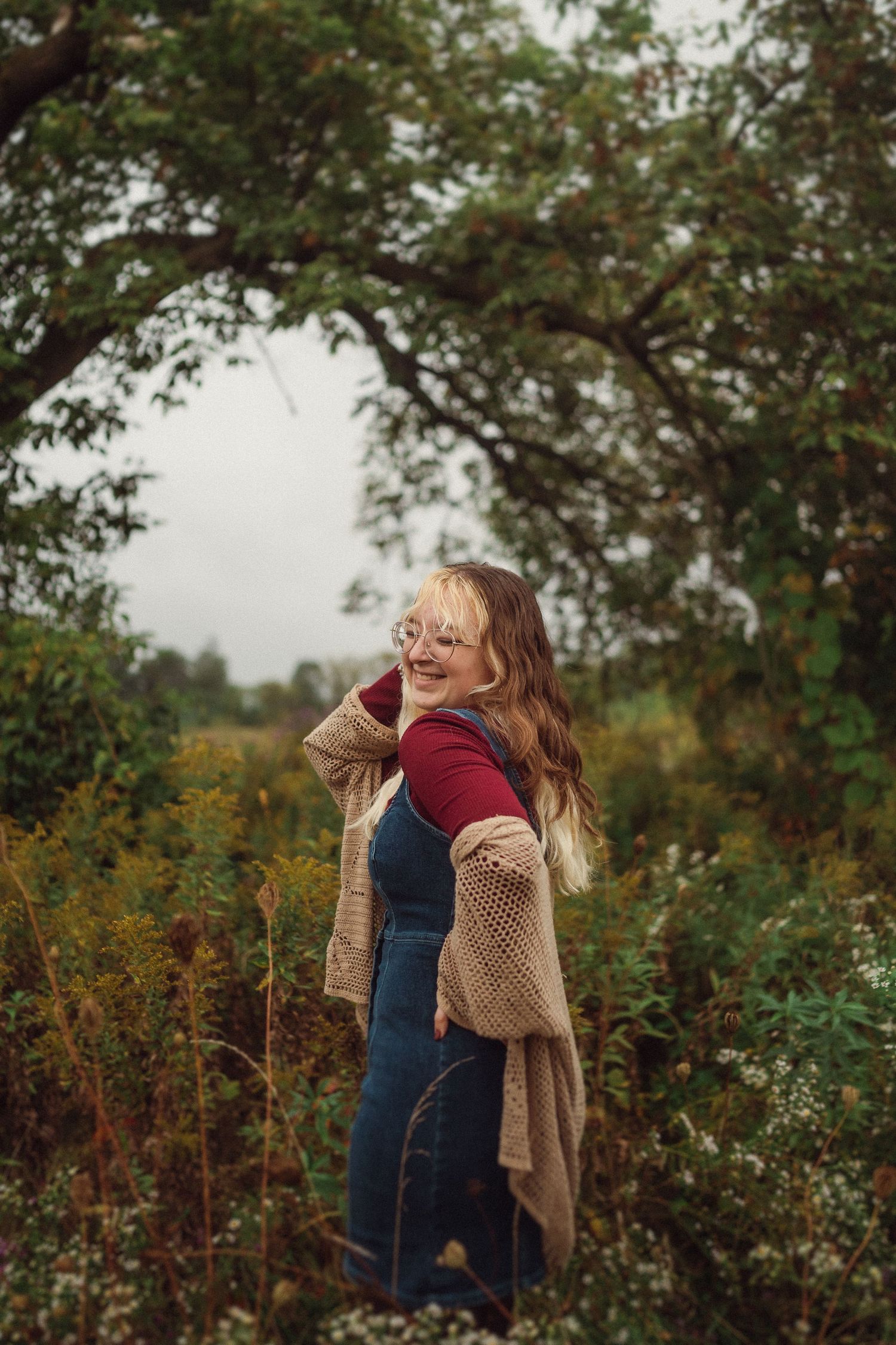 Outdoor autumn portrait featuring someone in a red sweater and cozy cardigan surrounded by nature.