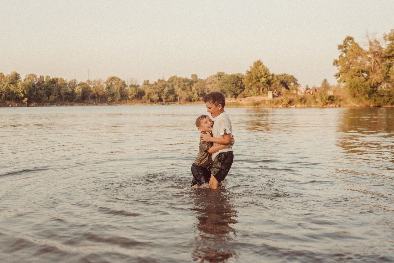 Parent and child sharing a tender moment while standing in a lake during golden hour.