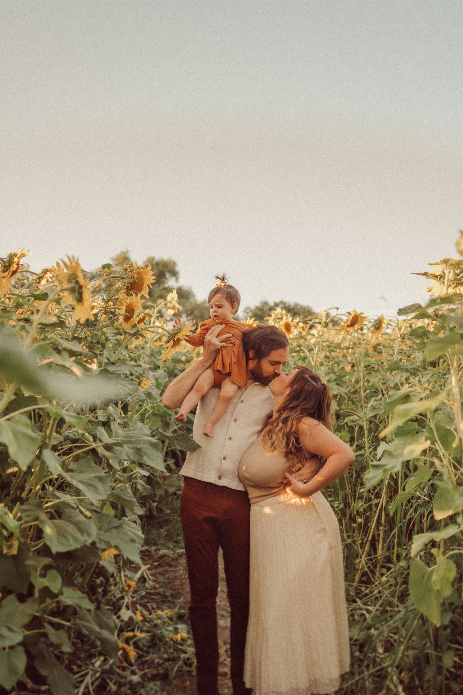 Family enjoying a sunset photoshoot amongst blooming sunflowers.