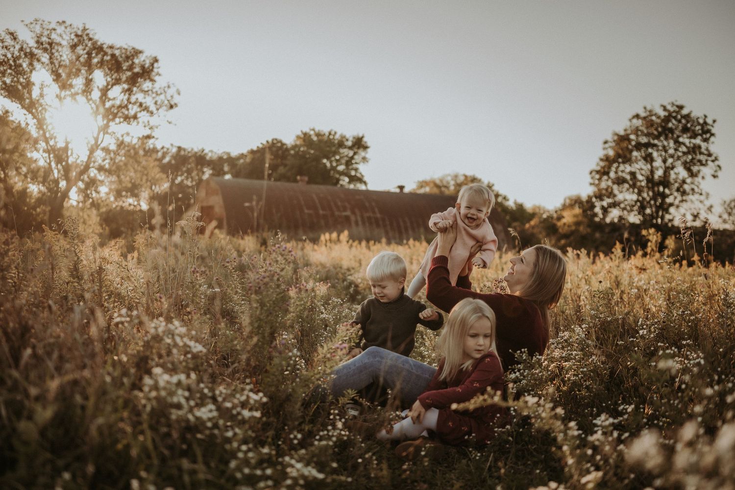 Candid family moment captured in a golden field during sunset.