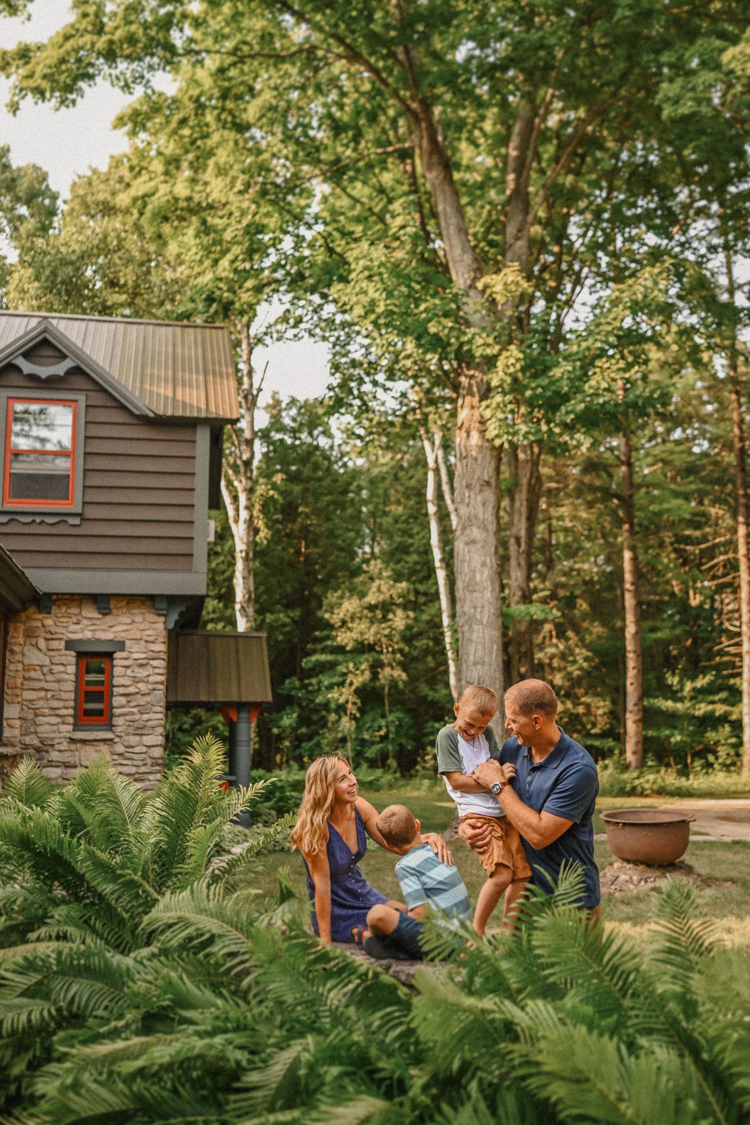 Family enjoying quality time together in garden with rustic cabin backdrop.