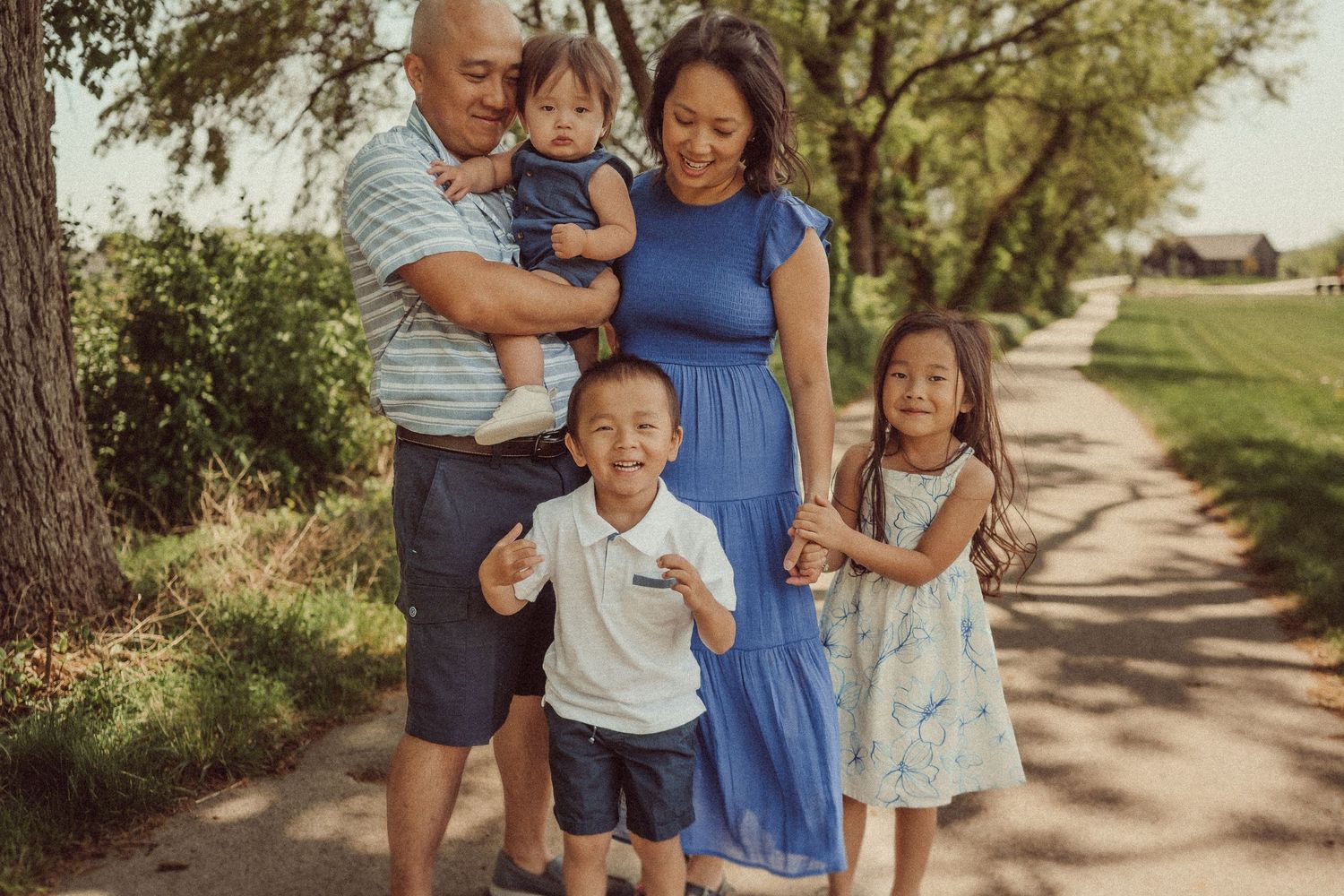 Family standing together on a beautiful tree-lined path for a portrait.
