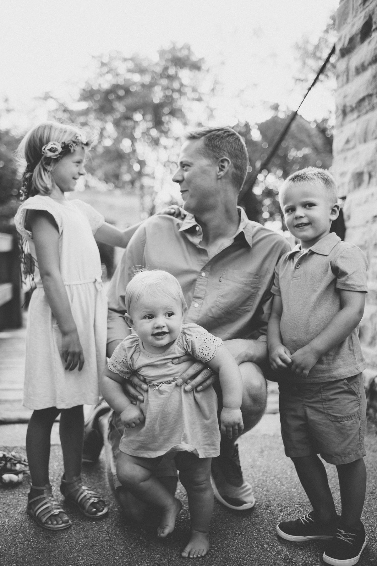 A black and white candid family moment outdoors showing playful interaction.
