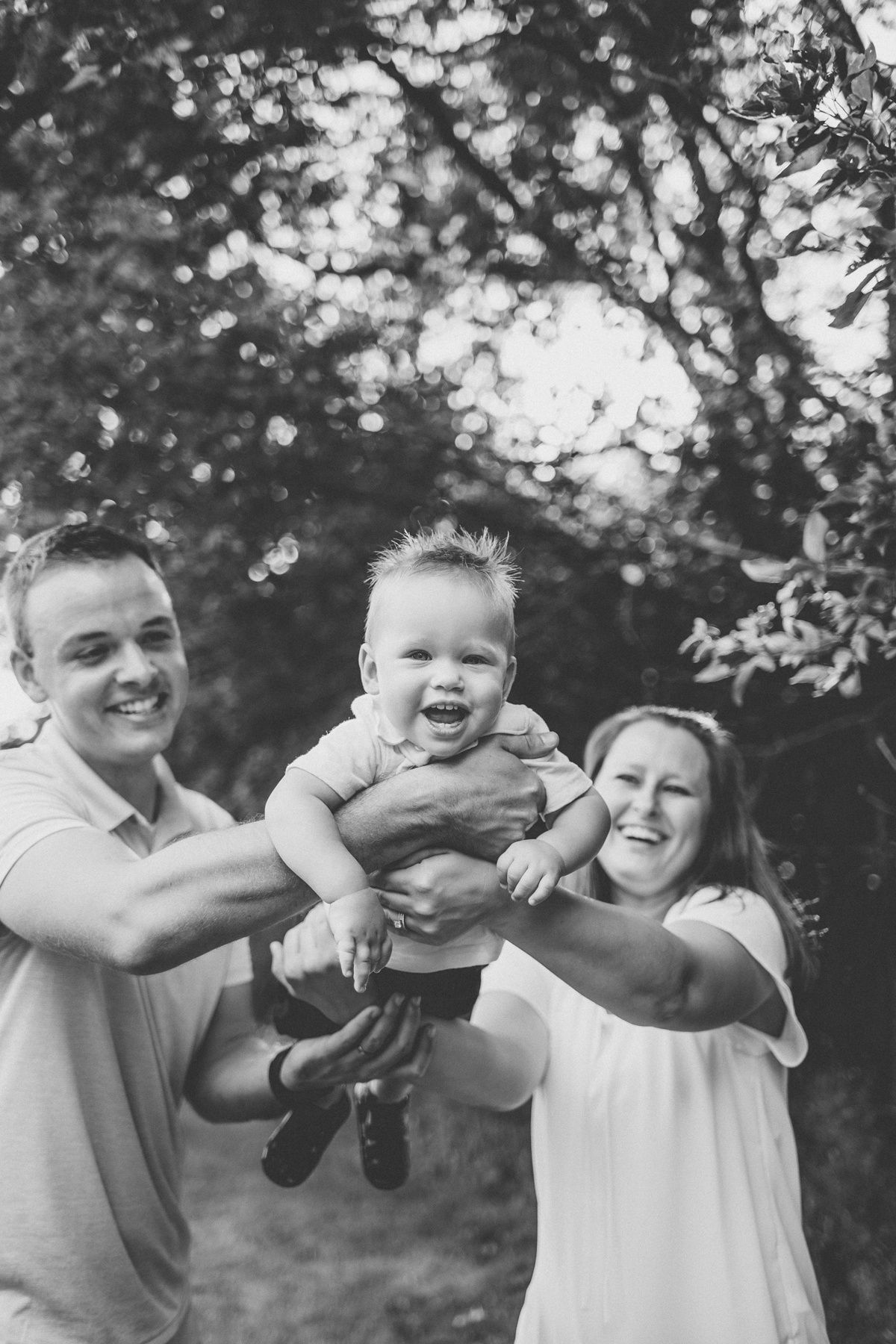 Black and white candid family photo showing playful moment outdoors.