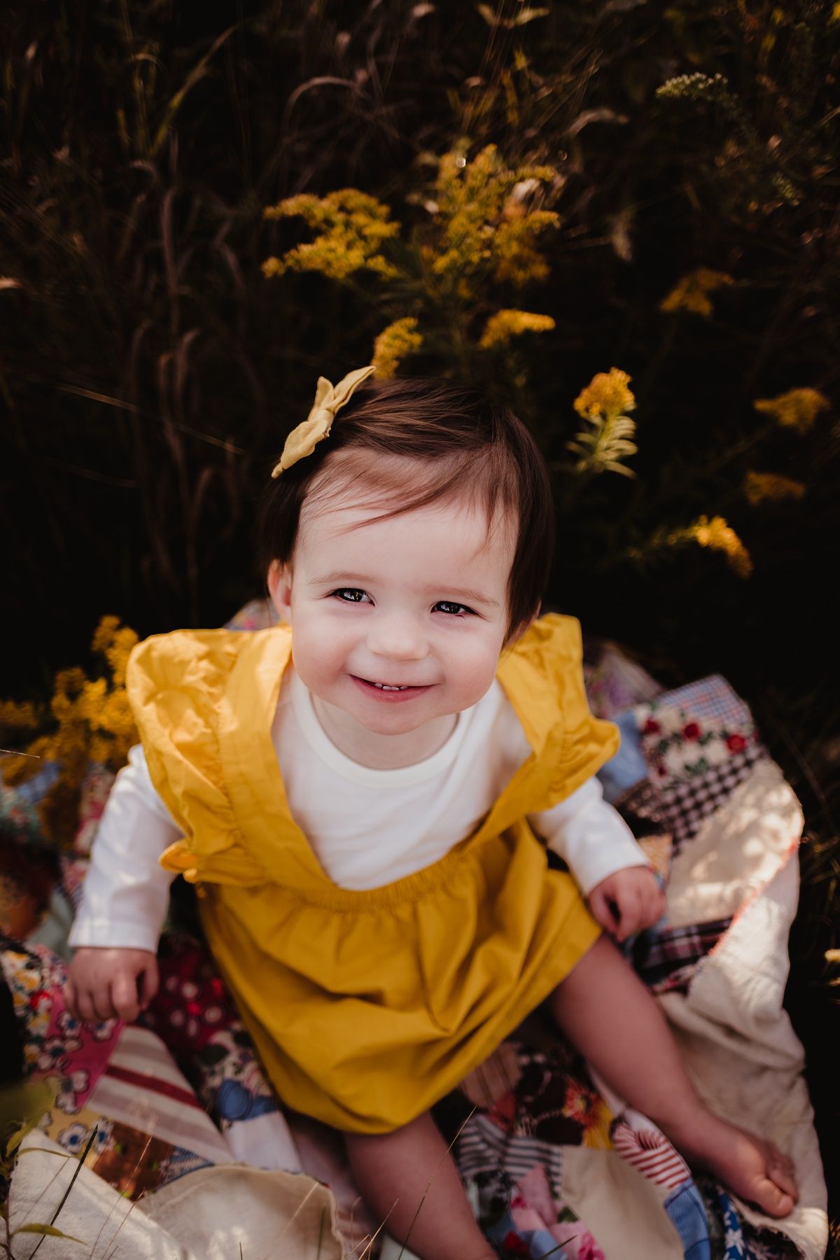Autumn portrait featuring bright yellow dress on patchwork quilt with golden flowers.