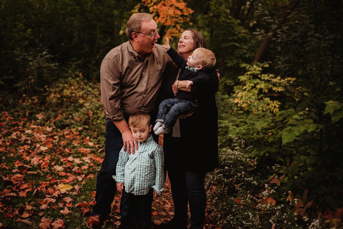 Family sharing playful moment together among autumn leaves.