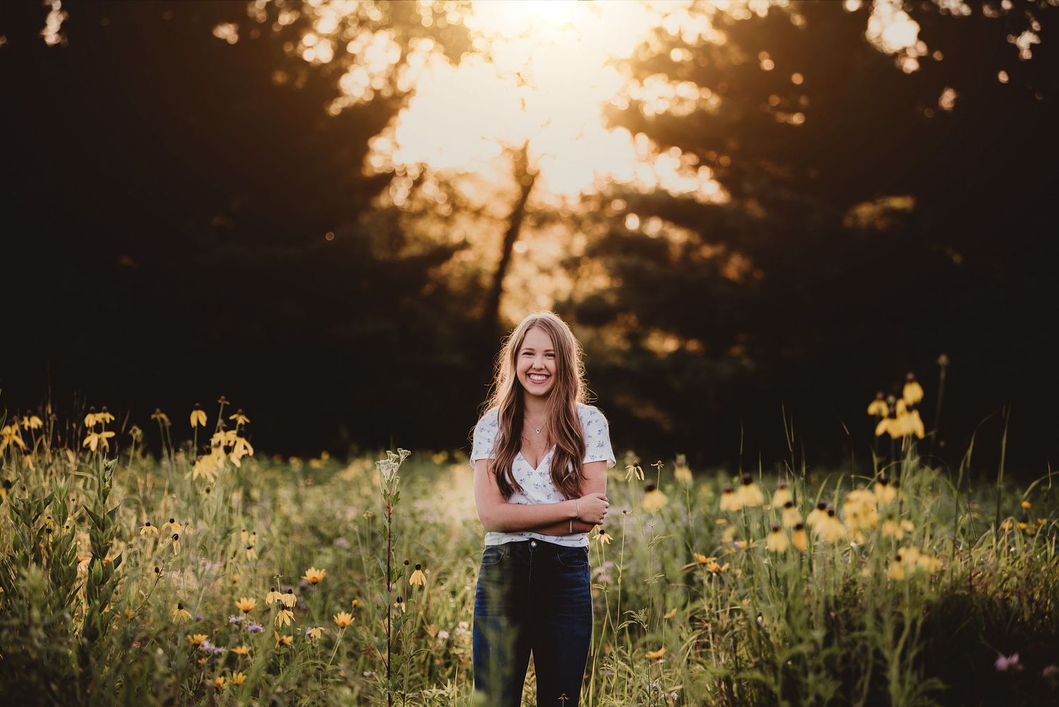 Woman standing in golden sunlit meadow with wildflowers at sunset.