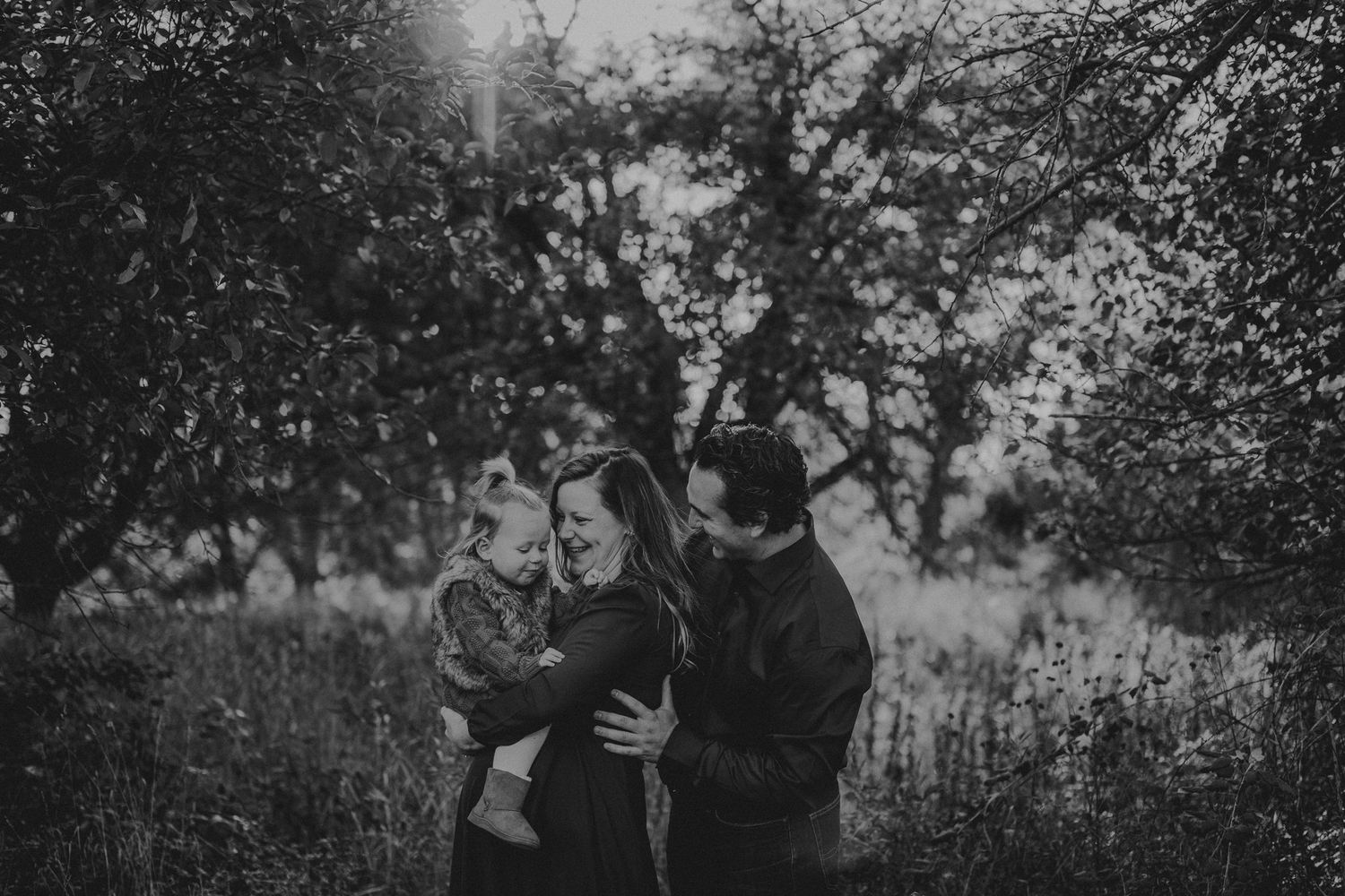 Black and white outdoor portrait showing tender moment between figures in natural setting.