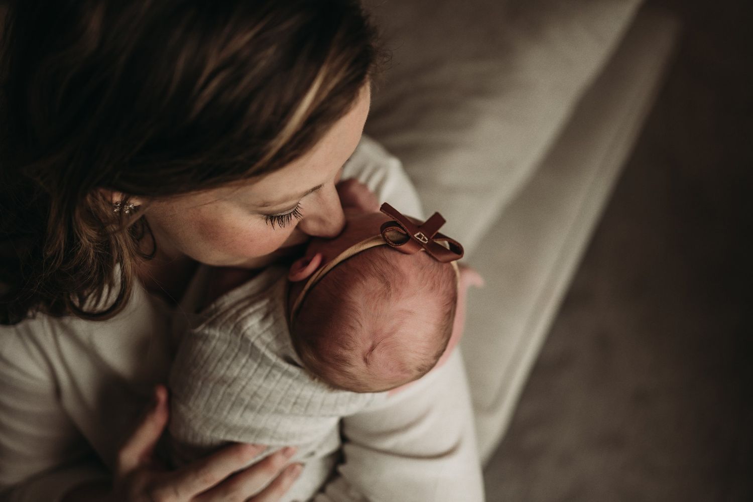 Close-up of parent gently kissing newborn baby's head.