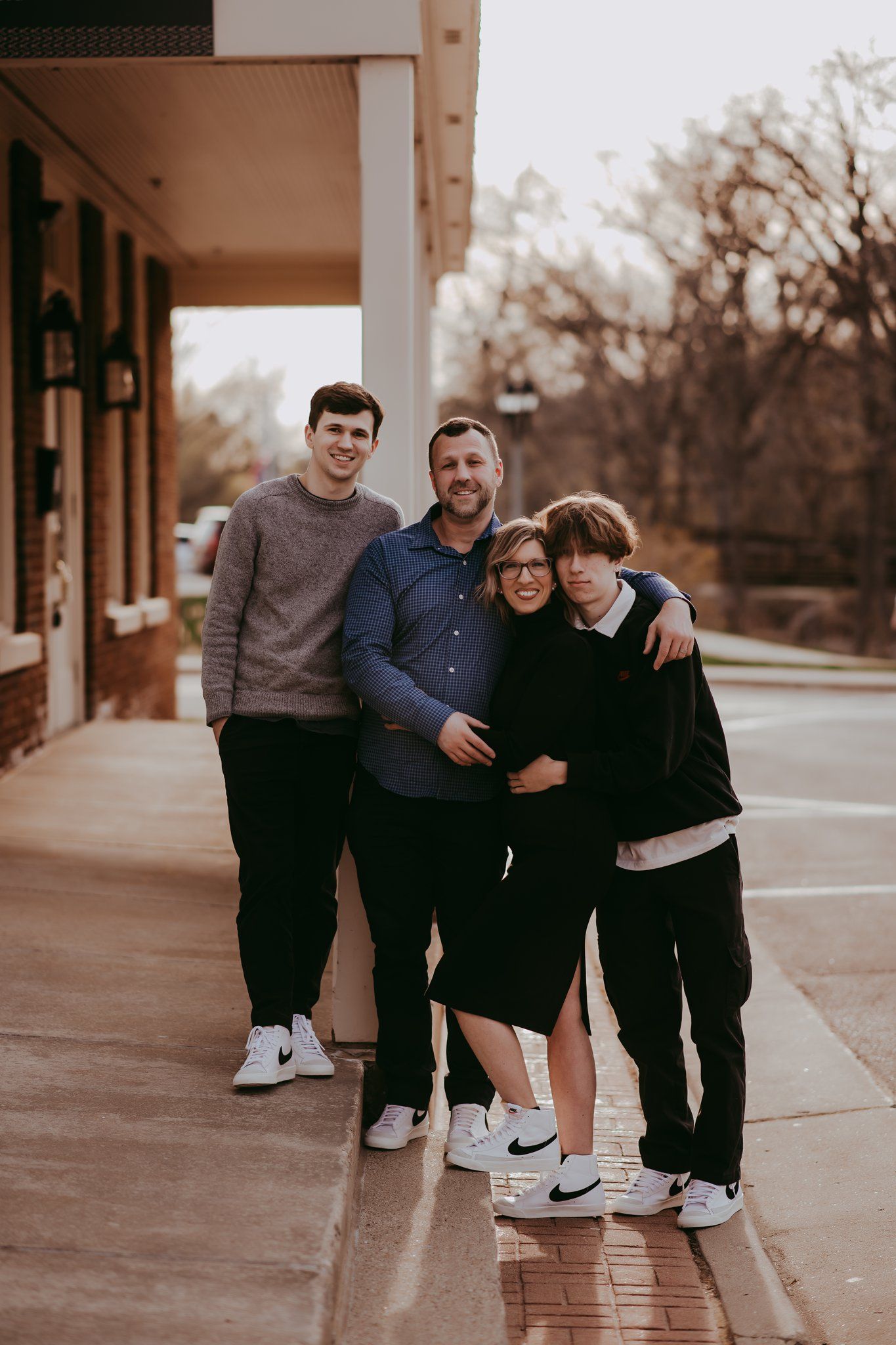 A small group stands close together for a photo outside a brick building with columns.