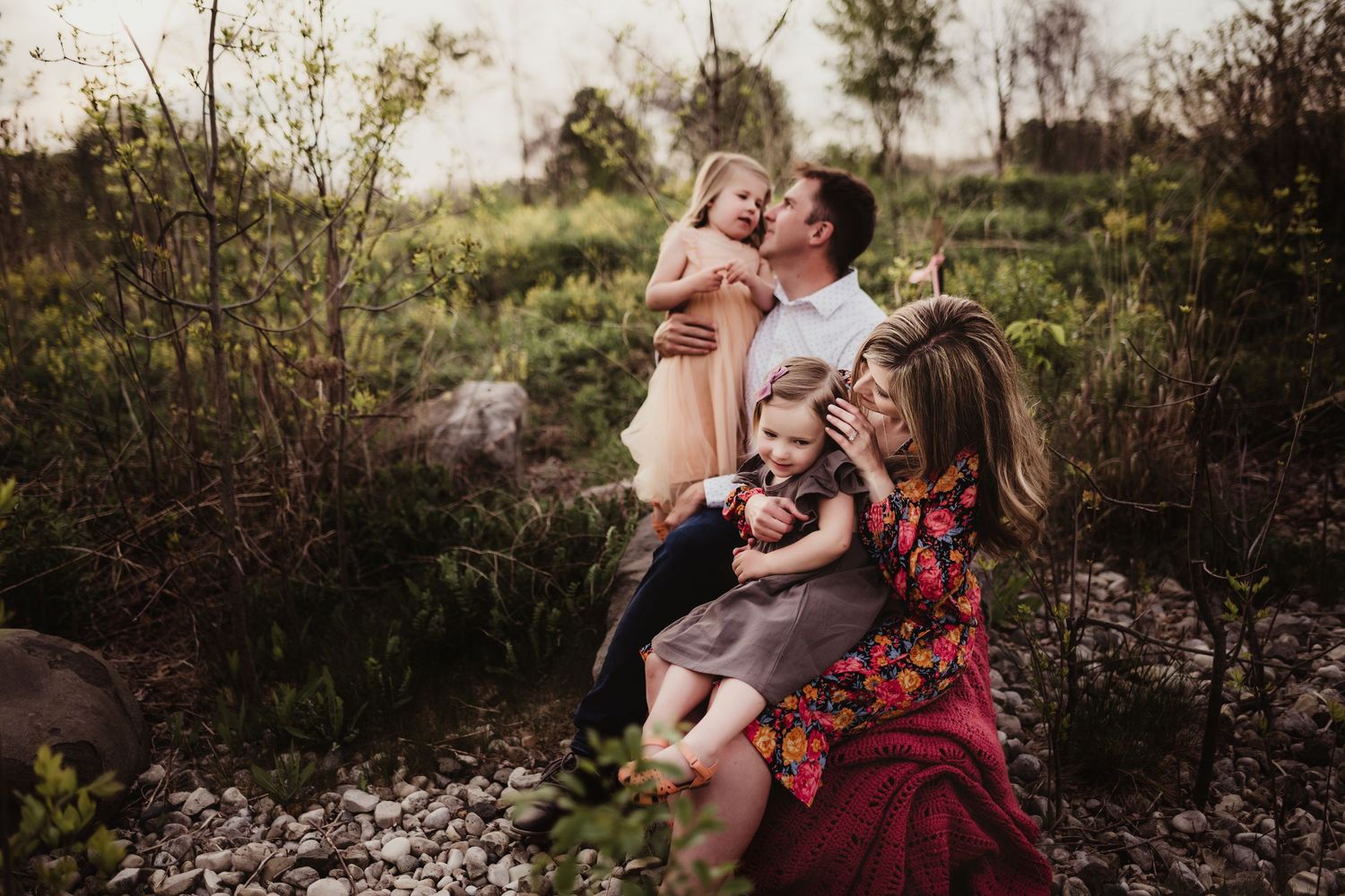Candid outdoor family portrait in natural setting with wild grass and evening light.