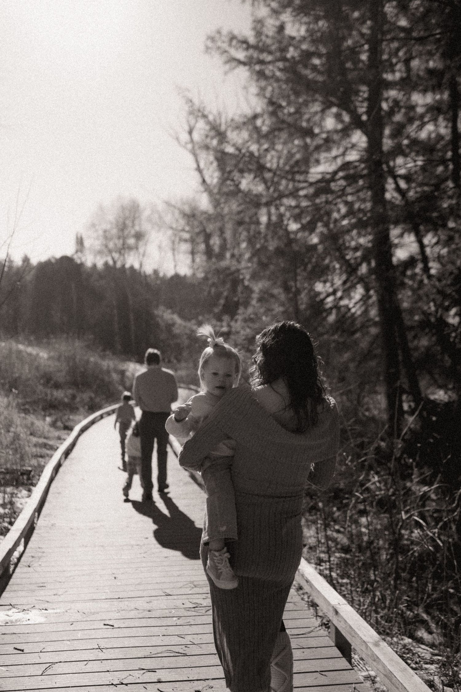 Silhouettes walking together on a wooden boardwalk through nature.