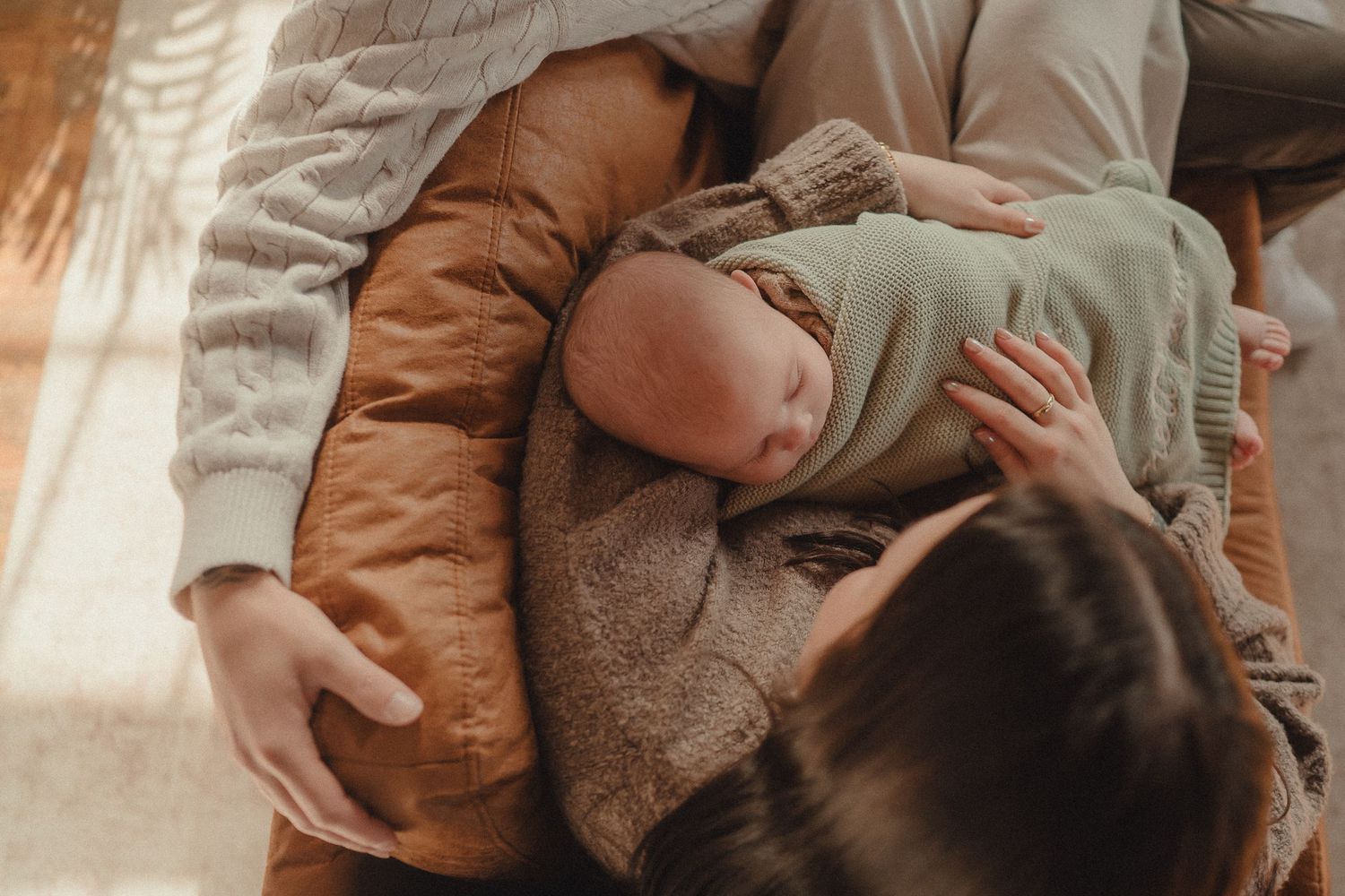 Intimate candid moments captured on a leather sofa in warm, natural lighting.