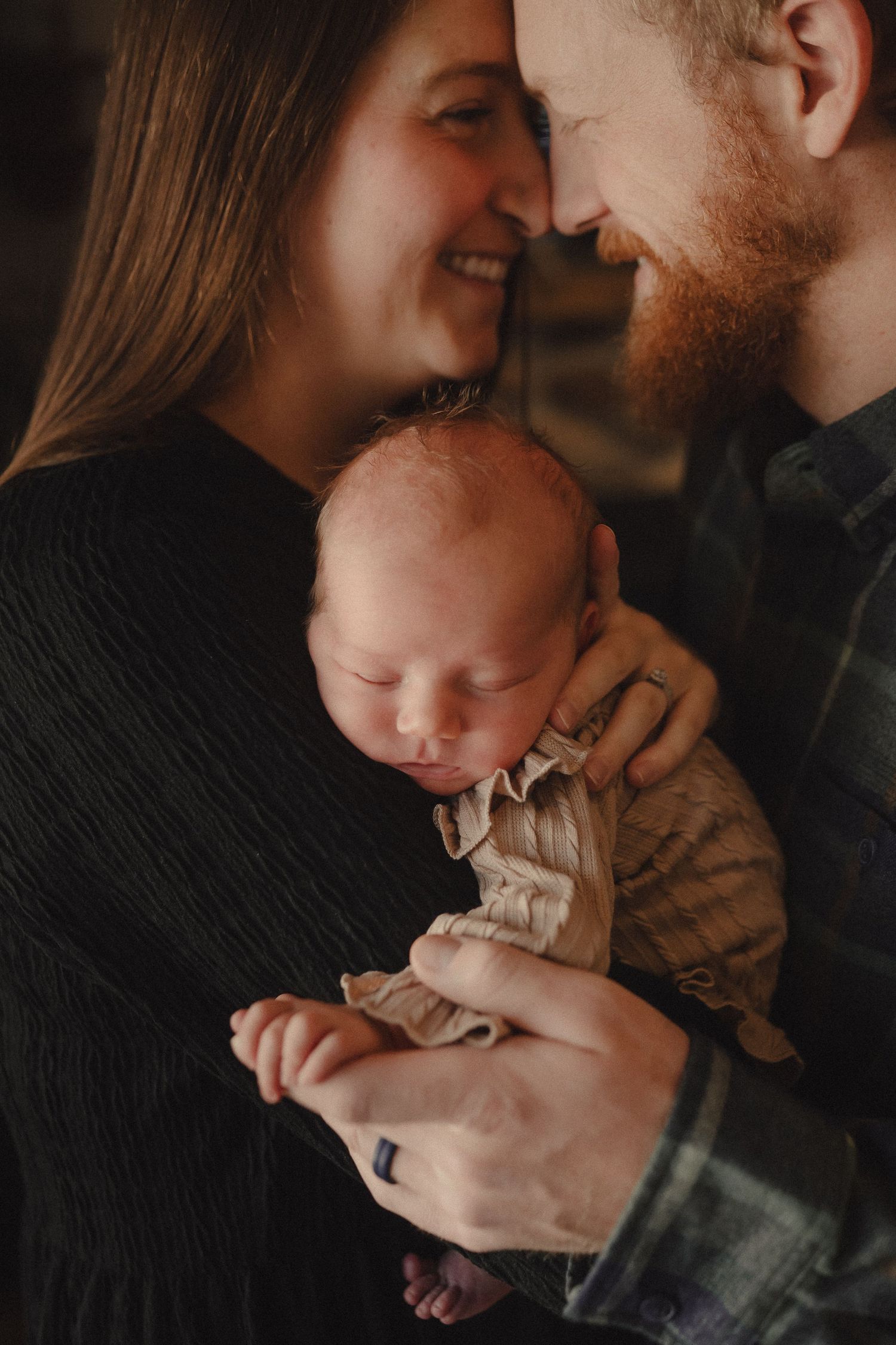 Intimate family portraits showing gentle moments and cuddles in a dimly lit indoor setting.
