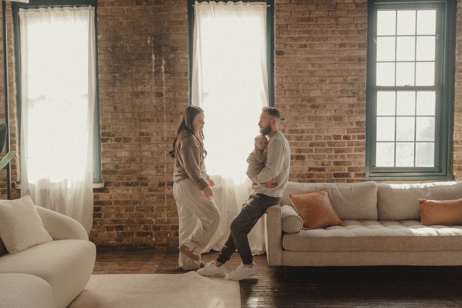 Family photography session in an industrial space with exposed brick walls and large windows.