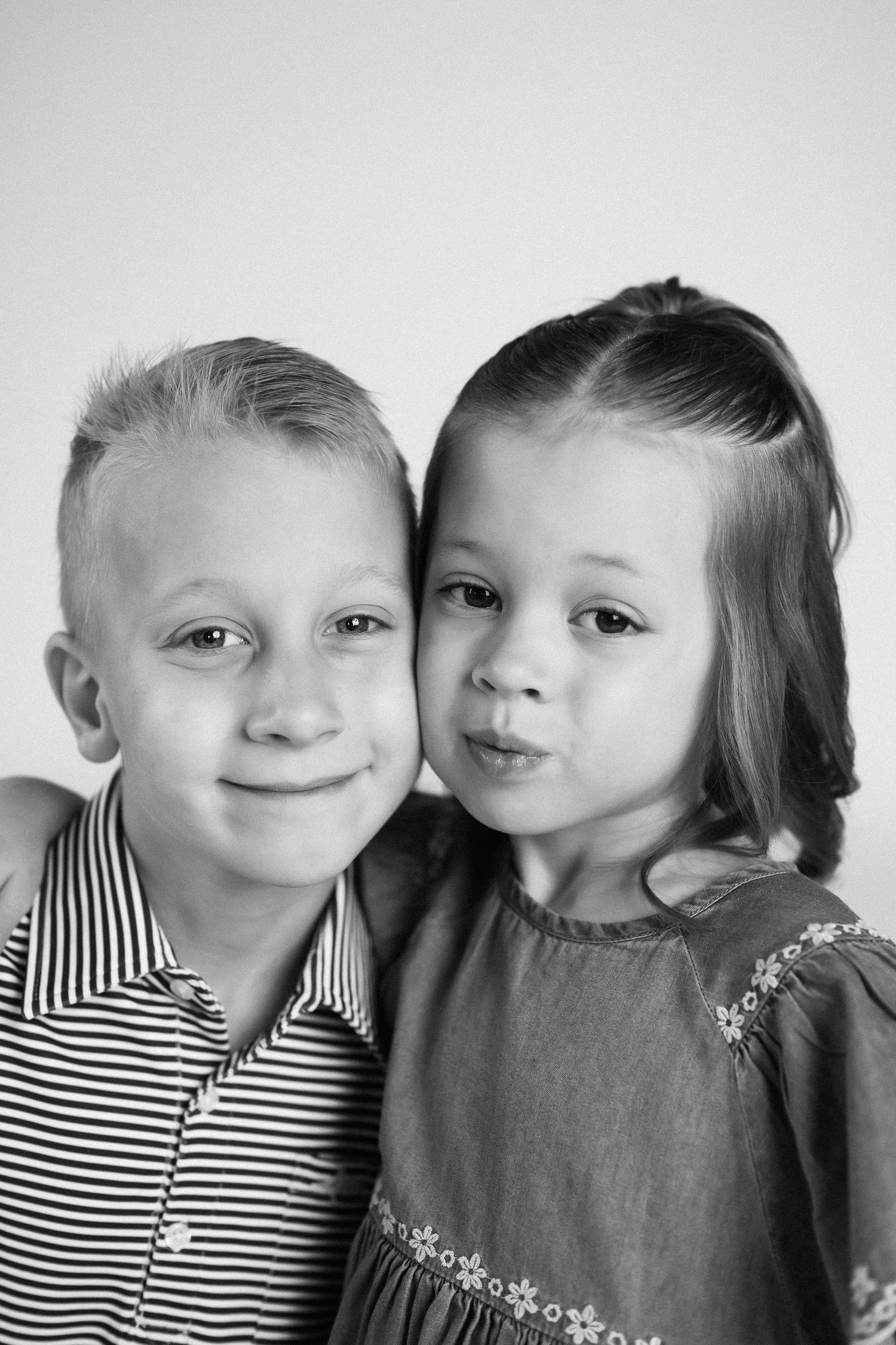 Black and white photo sequence of two children in striped shirt and gray dress posing together.