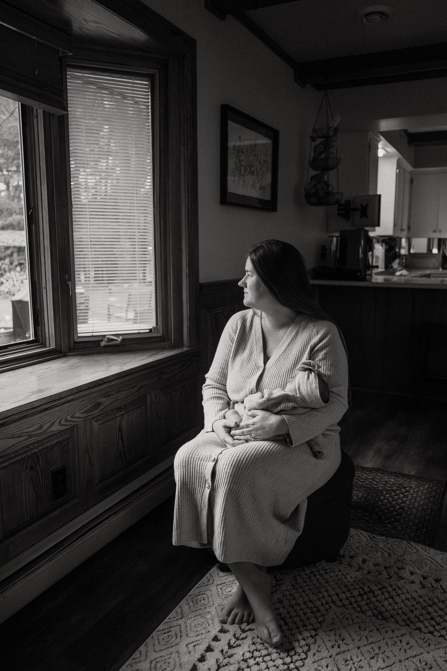 Artistic black and white portraits showing contemplative moments by window in living room.