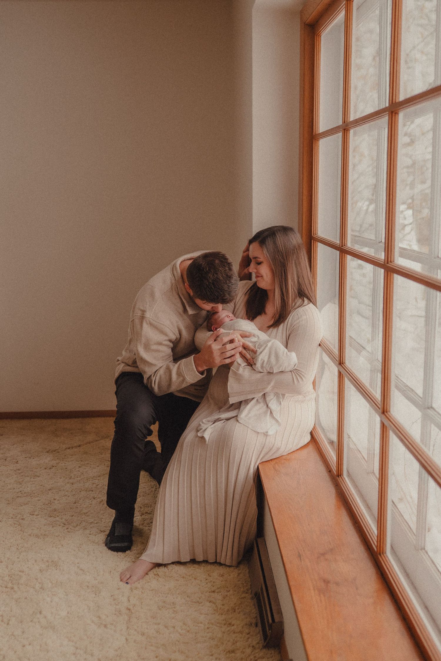 A series of intimate poses by a window with soft natural lighting and white clothing.