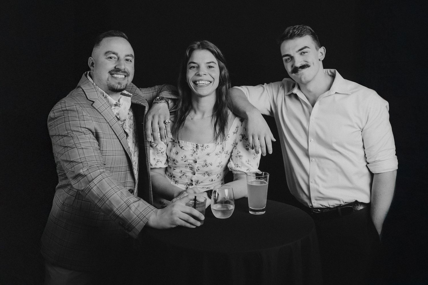 Black and white photo strip capturing friends sharing drinks and laughter together.