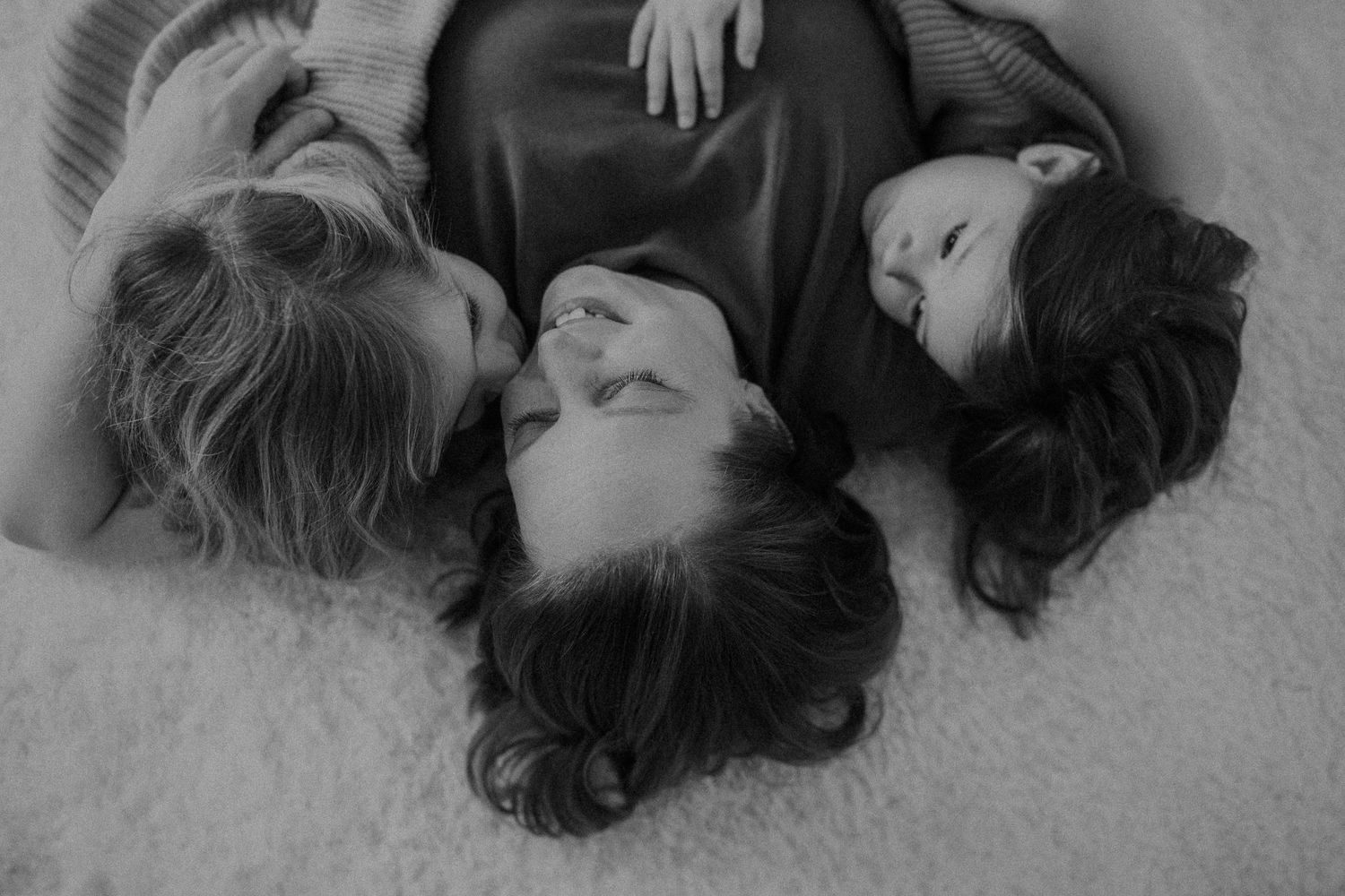 People lying on the floor with their heads together in a circle formation.