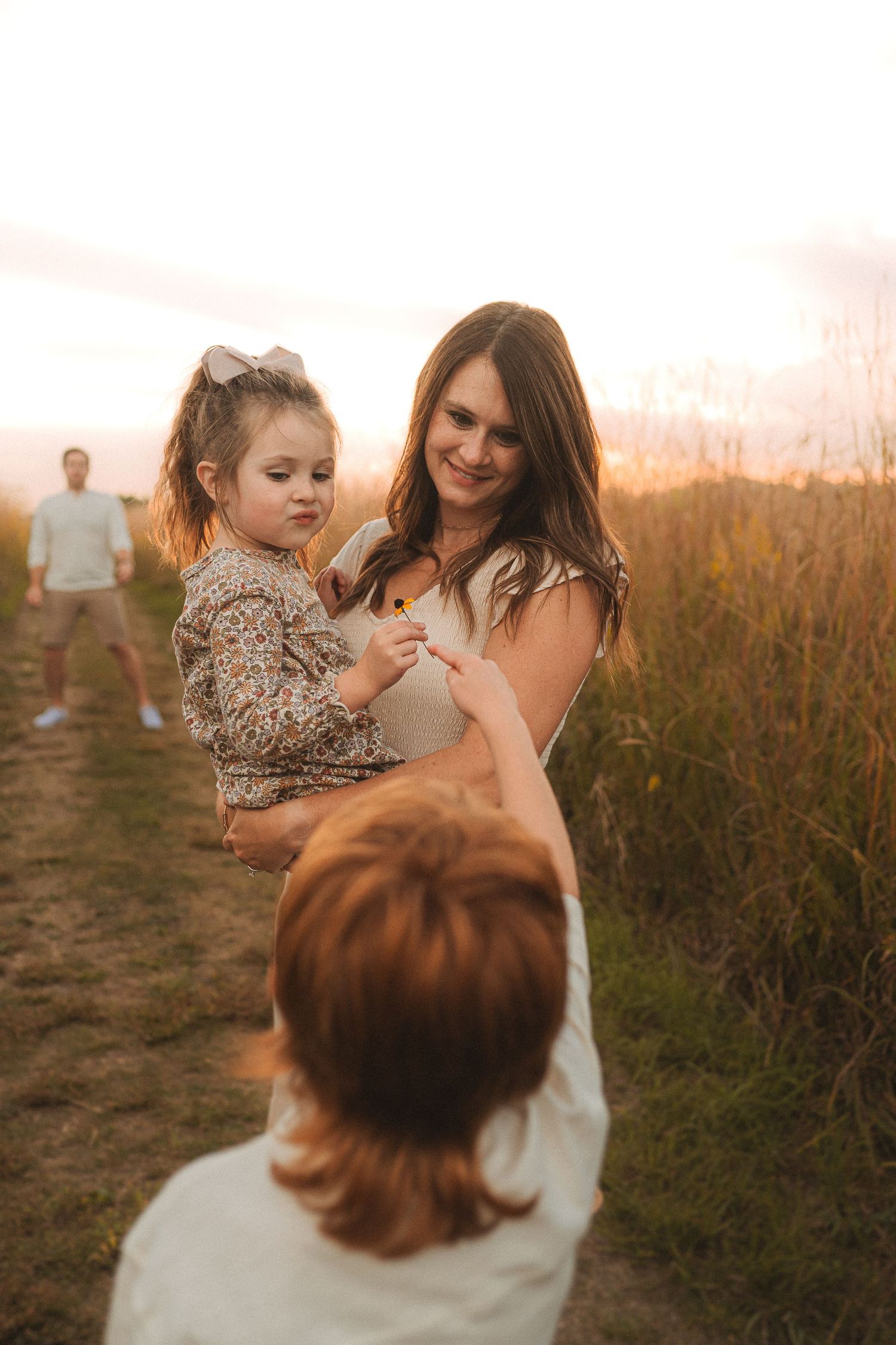 Candid family moment captured on nature trail during golden hour sunset.
