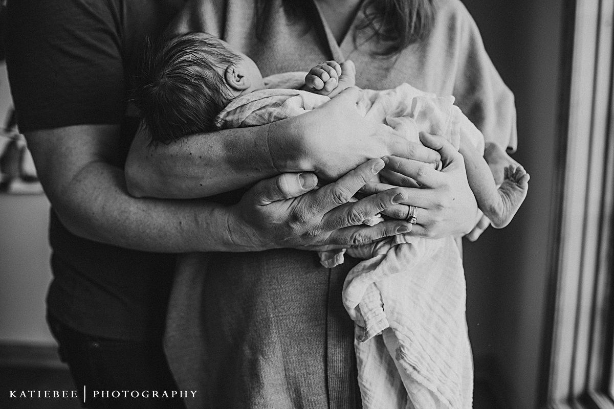 Black and white photo showing tender moment holding sleeping newborn baby.