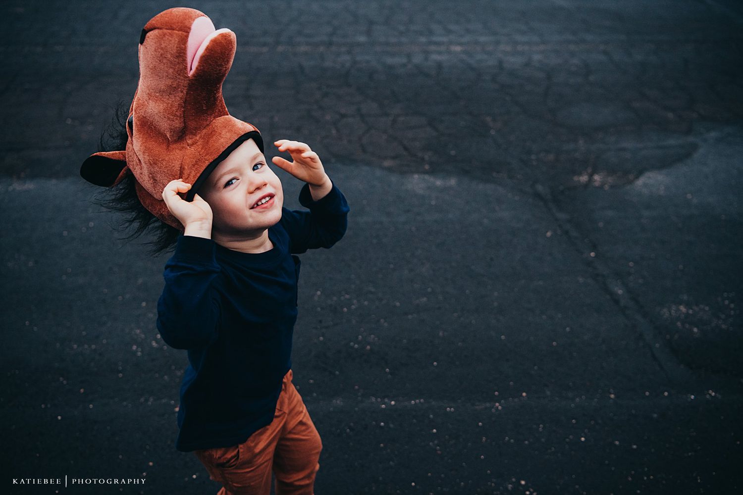 Child wearing fox hat plays expressively against dark background.