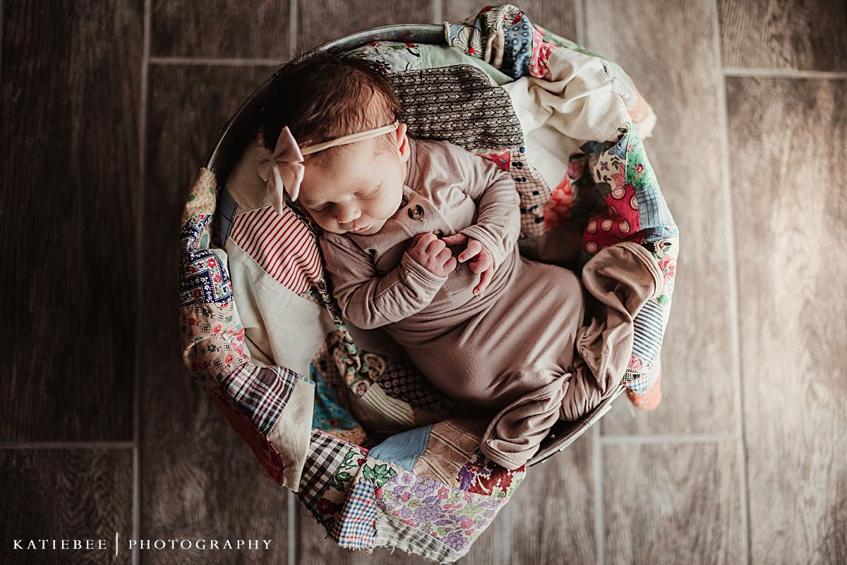 Overhead view of sleeping infant in beige clothing nestled in a patterned blanket.