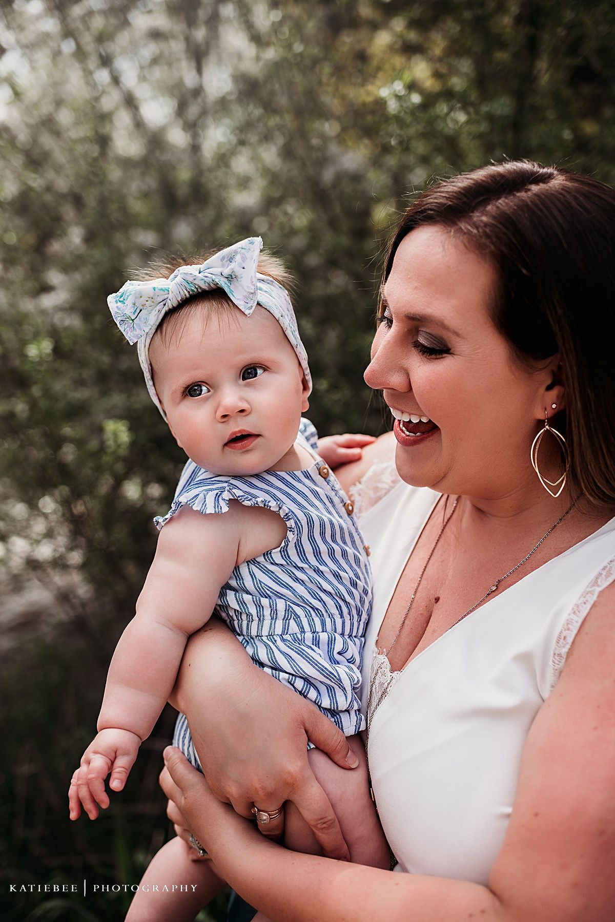 Candid outdoor portrait showing happy interaction with baby in blue striped outfit.