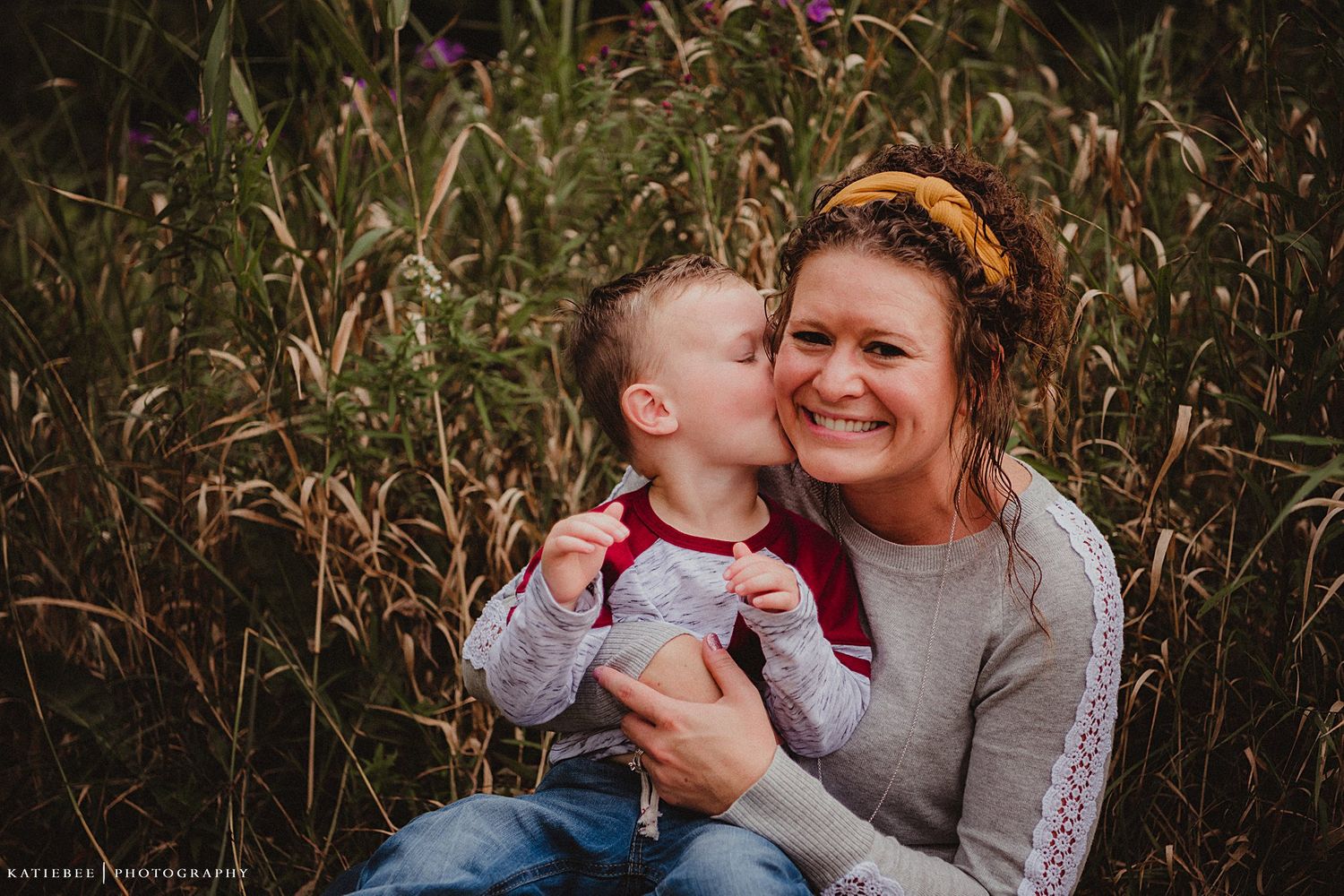 Sweet candid moment between two people outdoors among tall grass.