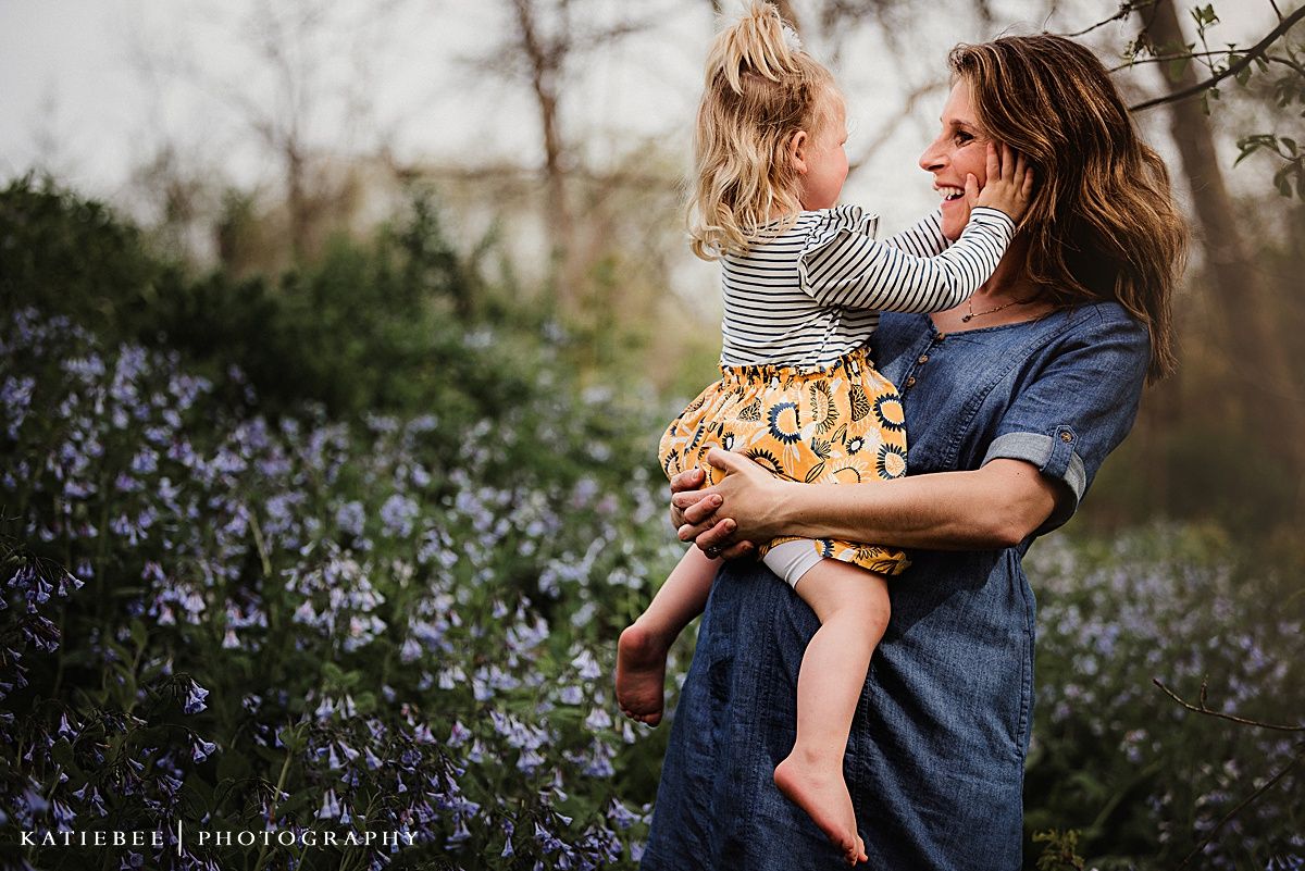 Sweet outdoor portrait surrounded by purple flowers showing a caring embrace.