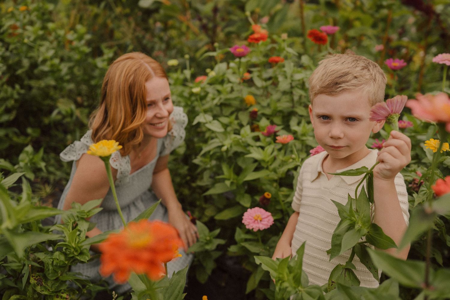 People enjoying a summer day in a lush garden with blooming rose bushes and vibrant flowers.