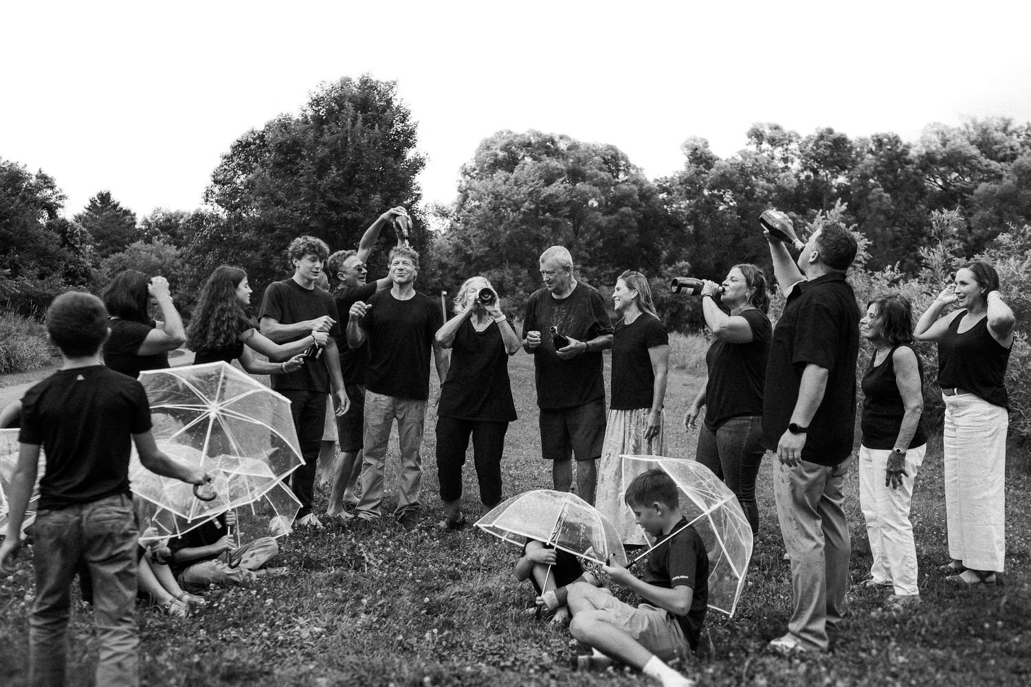 A black and white photo of people celebrating outdoors with dynamic poses and streamers.