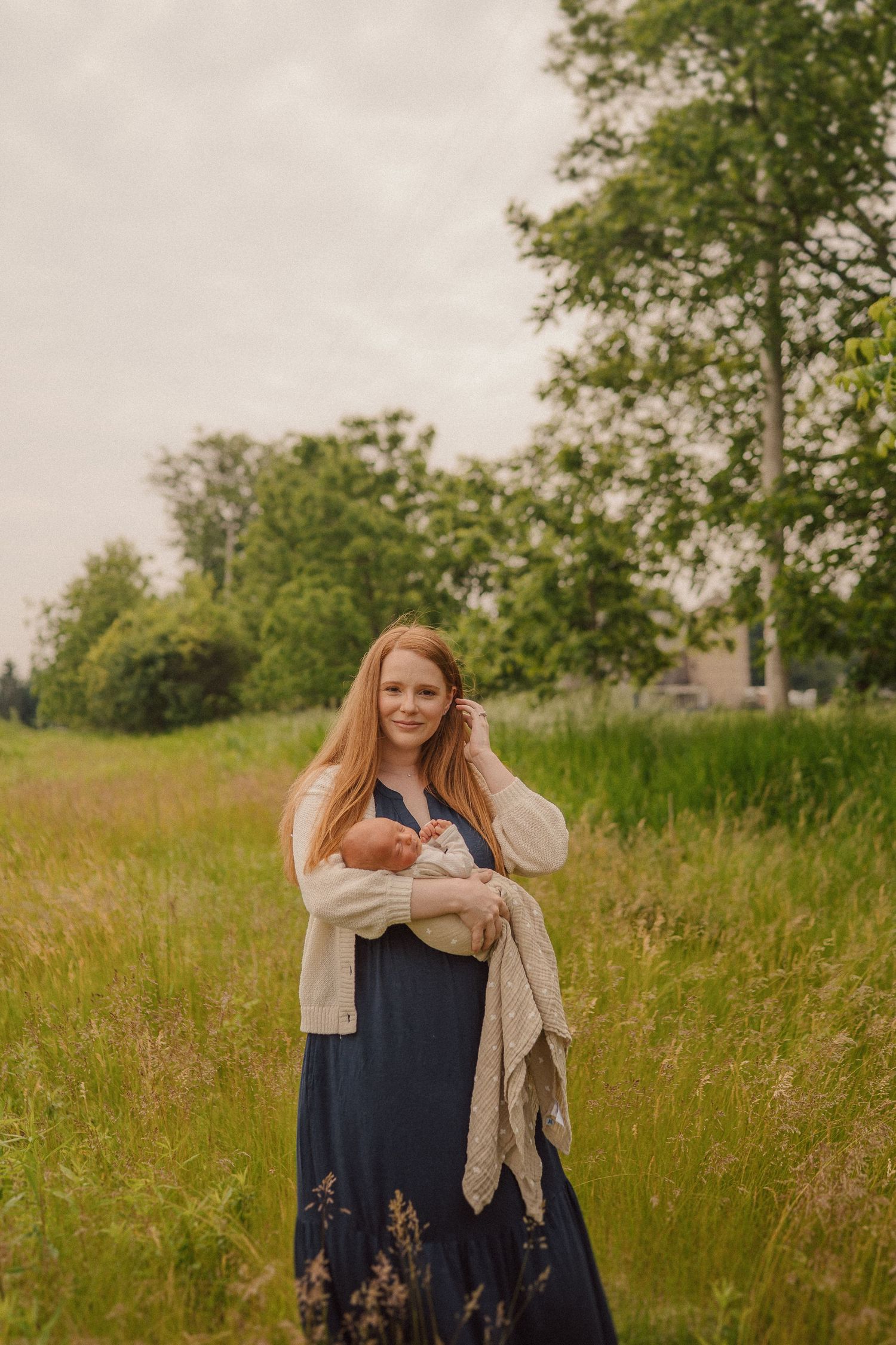 A dreamy outdoor scene features a navy blue dress and beige scarf amidst tall grassy meadow on a summer day.