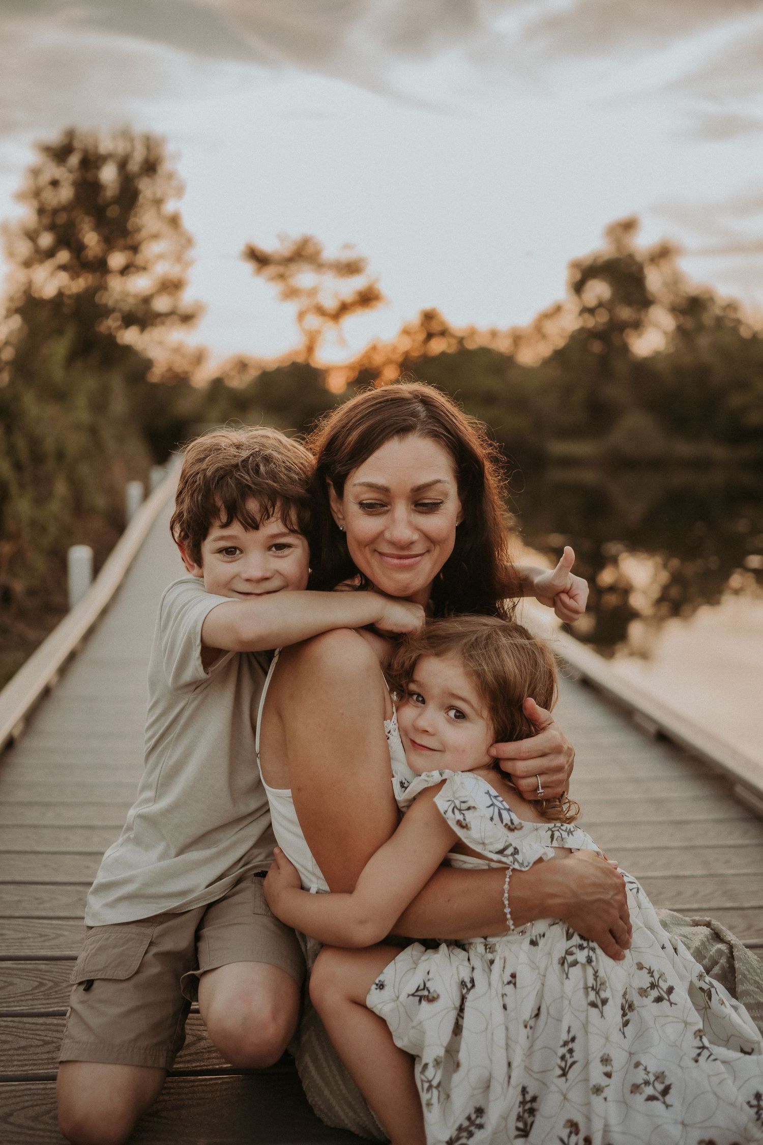 Joyful family portrait showing warm embraces on a wooden dock during sunset.