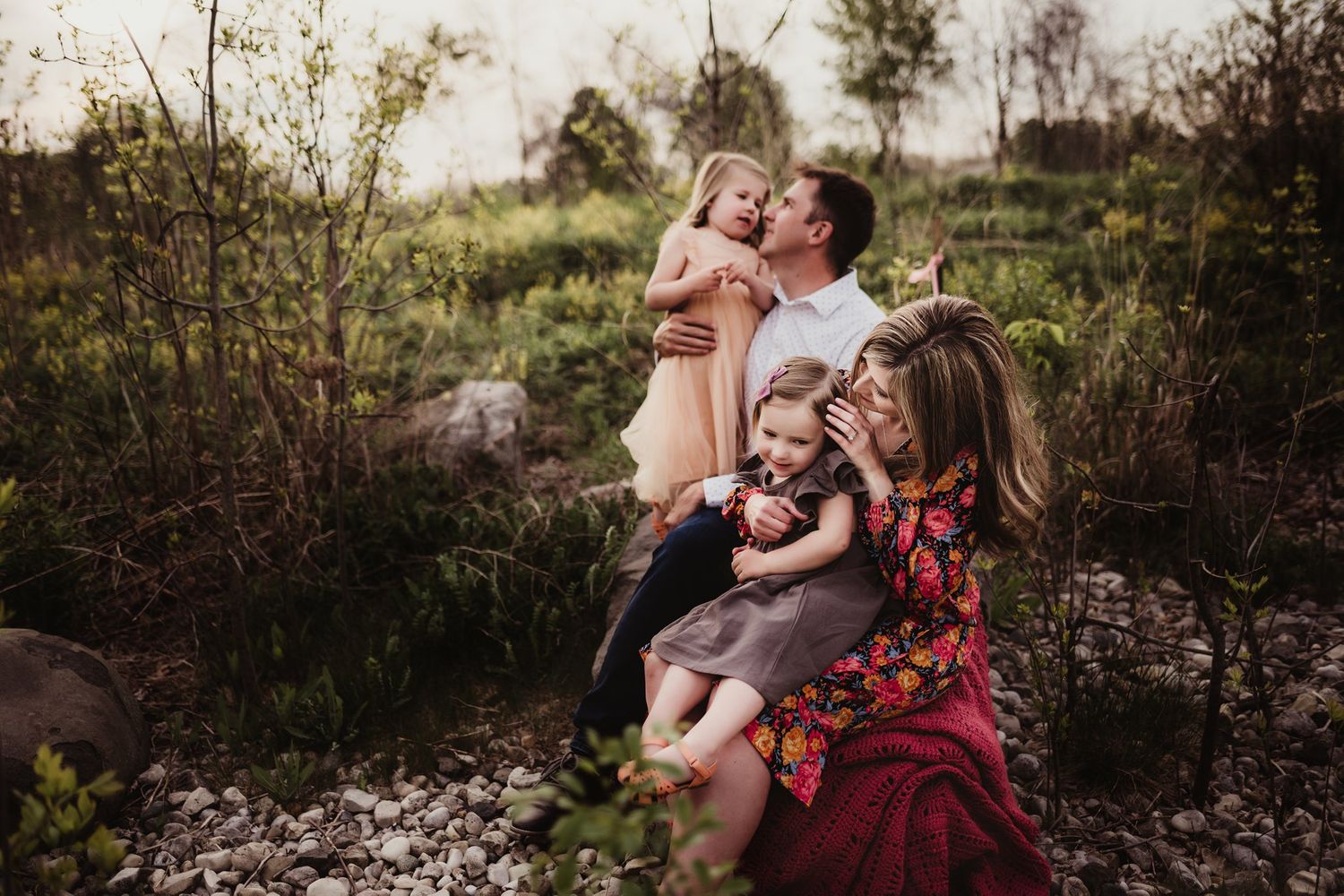 Beautiful outdoor autumn family photoshoot with warm tones among rocks and wildflowers at sunset.