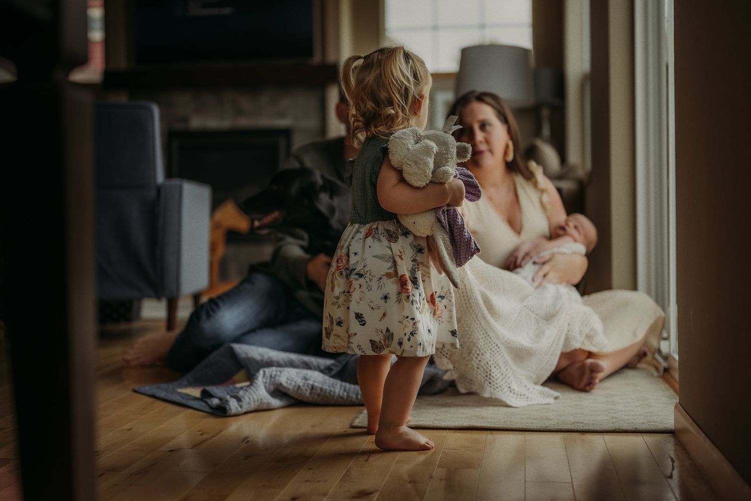 Heartwarming family moment with toddler and infant playing near a window.