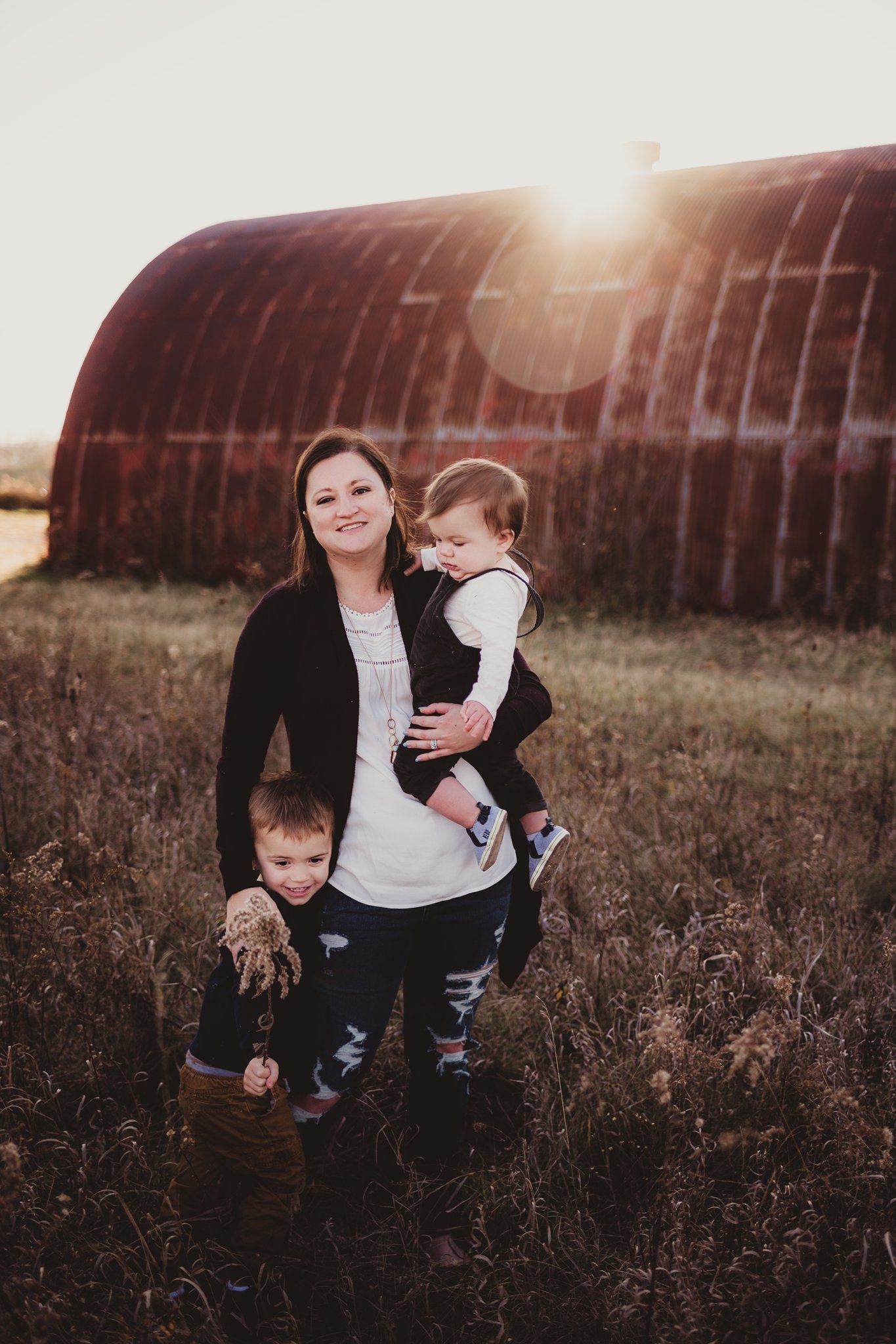 A family portrait captured at sunset against a rustic barn backdrop.