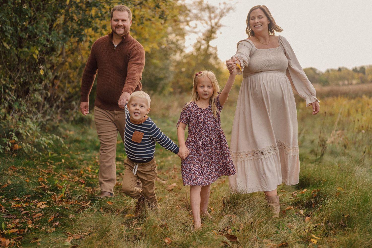 Family walking together through a scenic autumn meadow during golden hour.