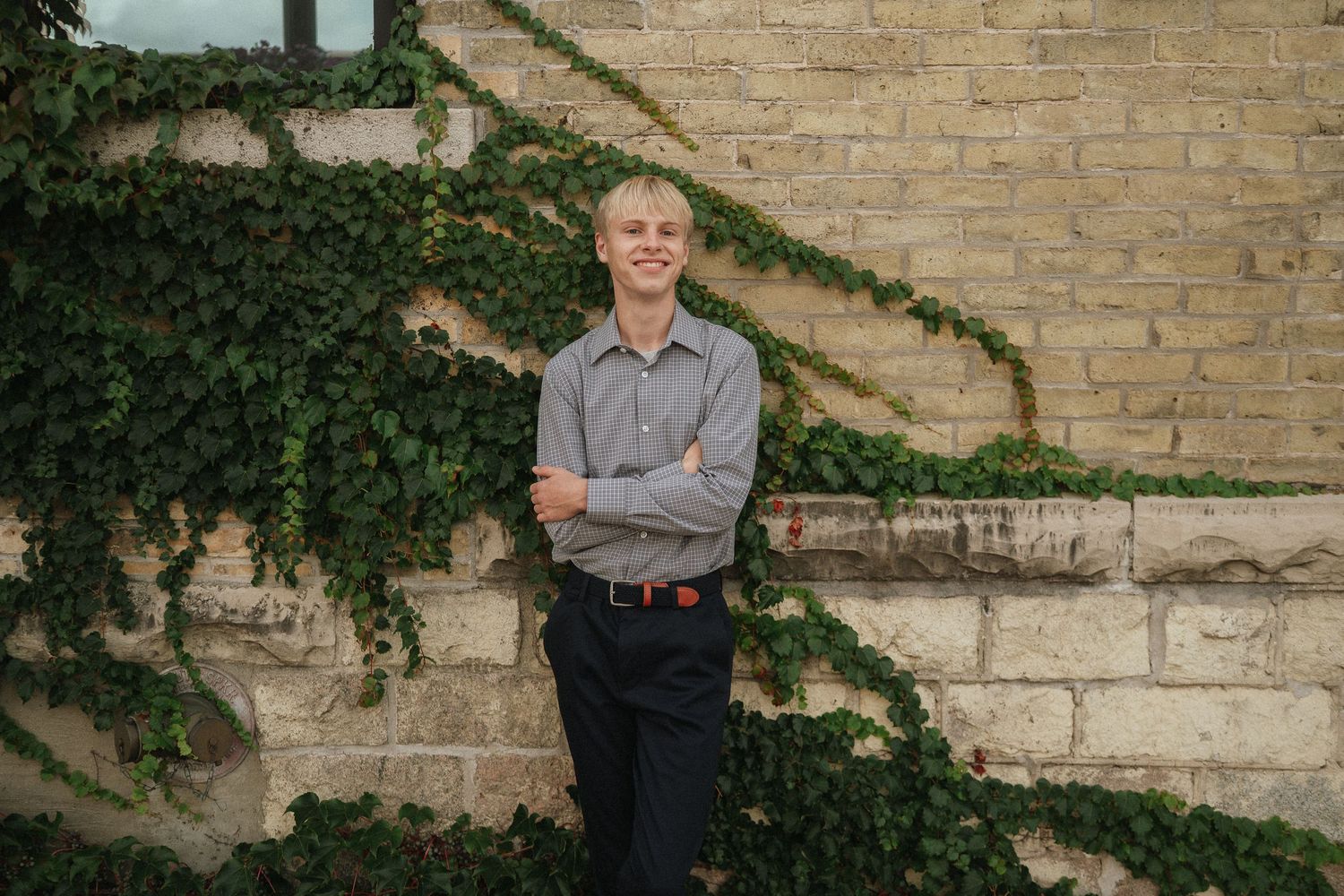 Outdoor portrait series against a brick wall with climbing ivy creating a natural backdrop.