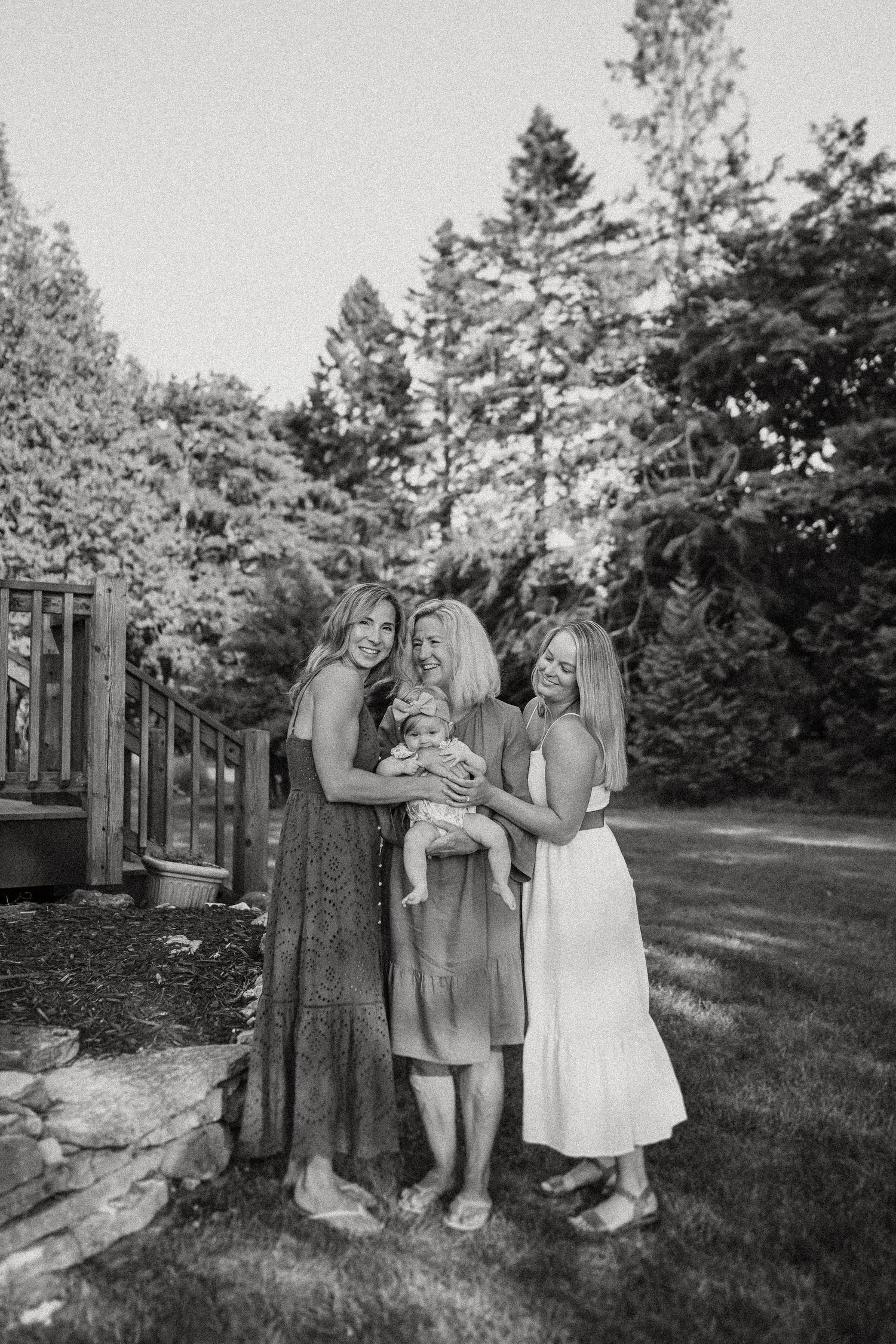 Black and white portrait of a family group standing together by a garden fence.