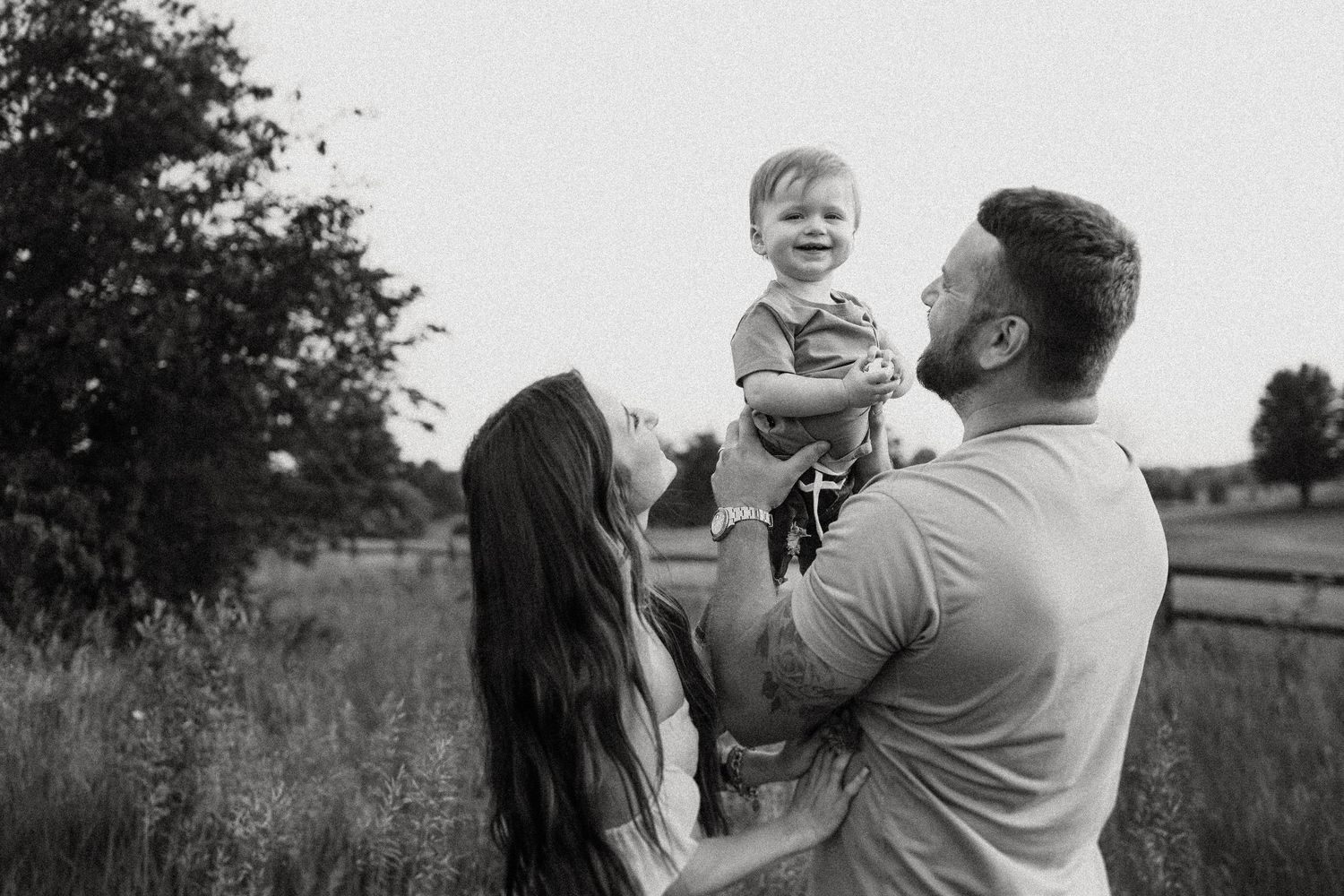Joyful family moment captured in black and white as they play together in an outdoor field setting.