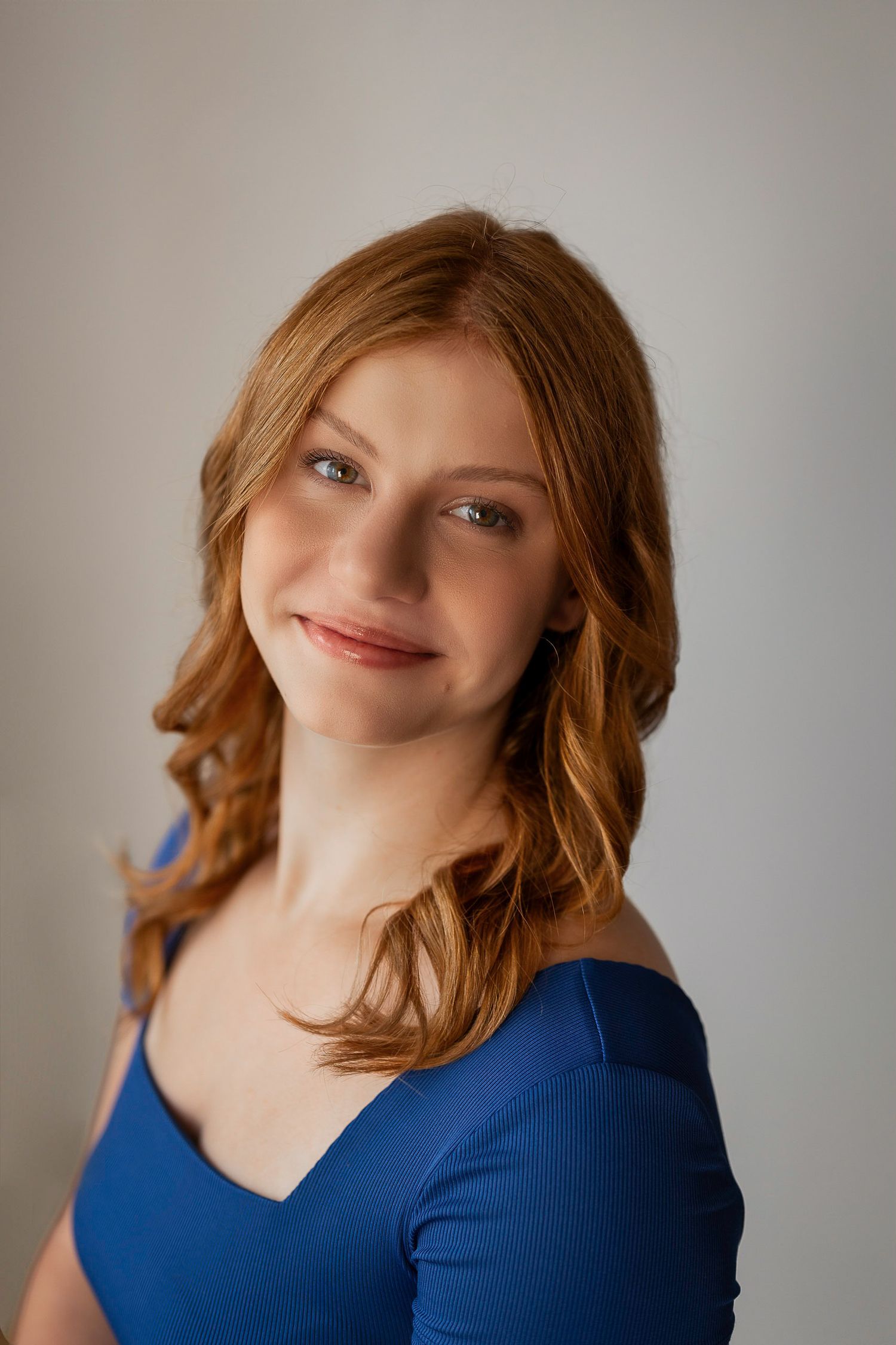 Professional portrait of person in blue top with soft lighting and warm expression.