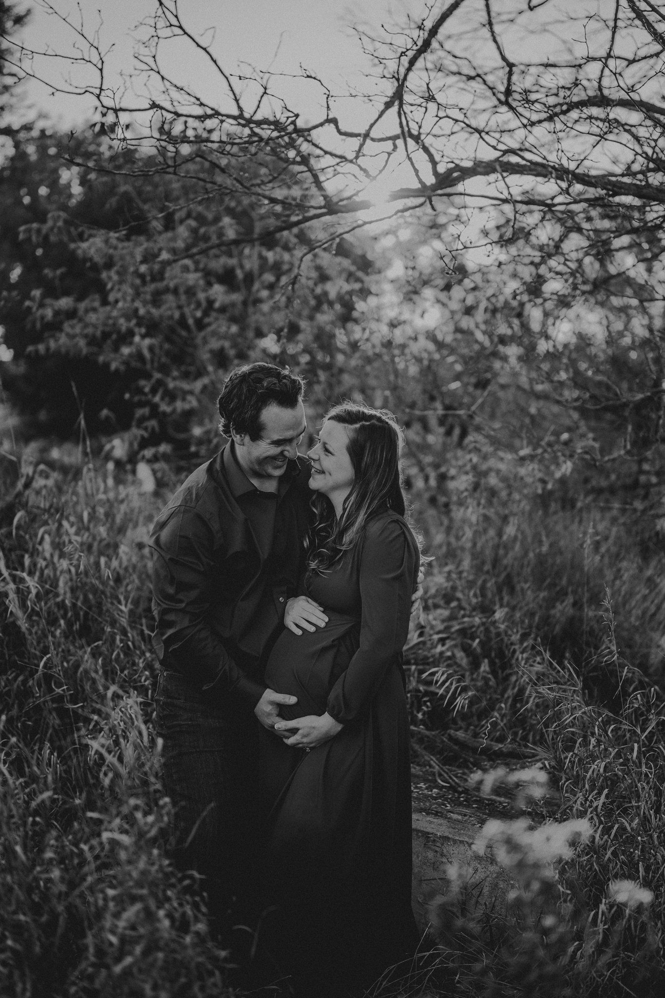 A black and white intimate maternity photo of a couple embracing outdoors.