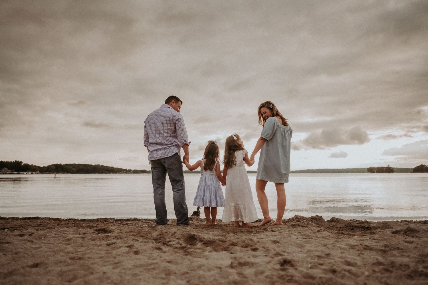 Family standing together watching the water at sunset on a moody beach.