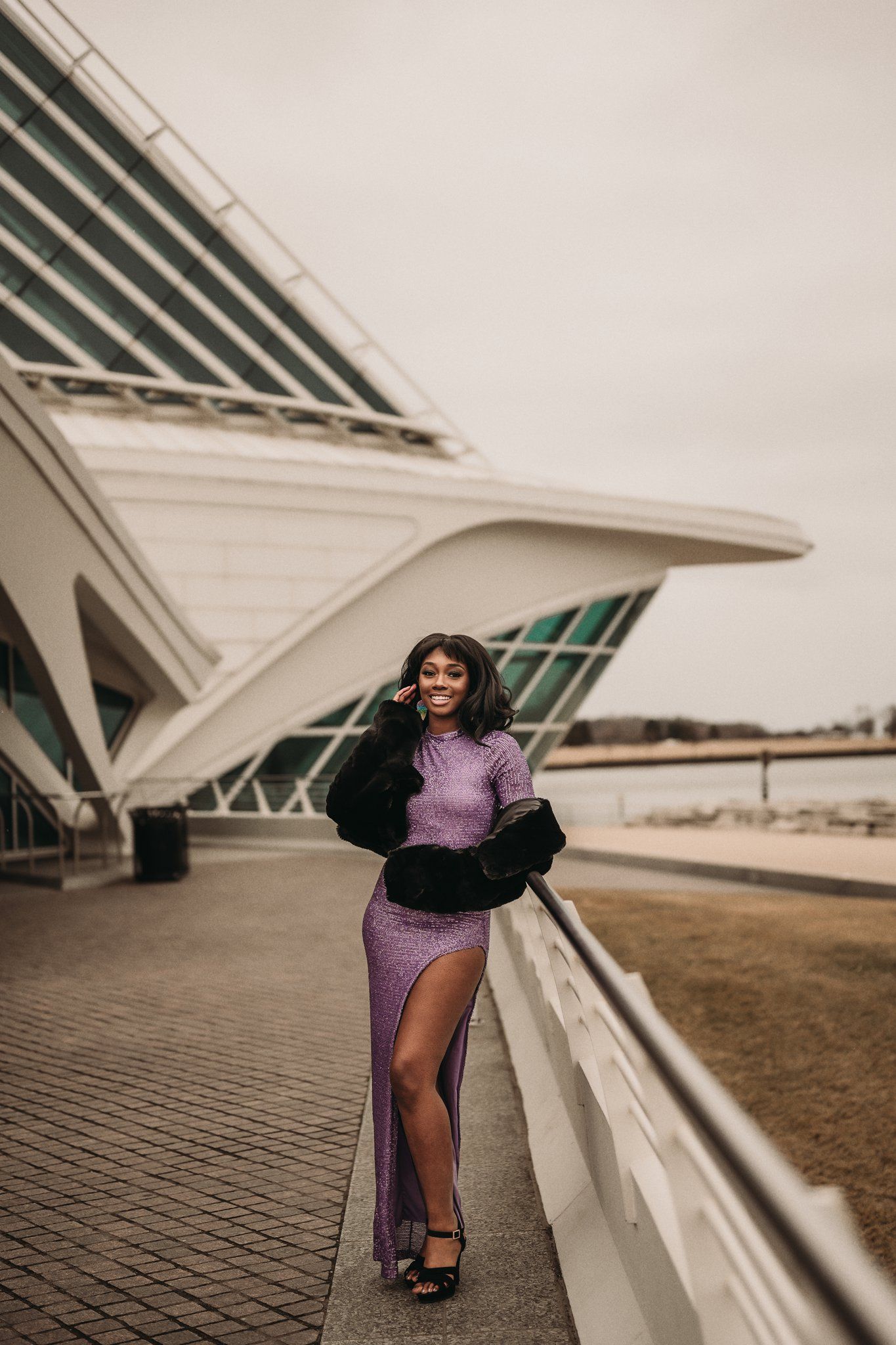 Pageant winner in purple gown poses outside Milwaukee Art Museum's distinctive architecture.