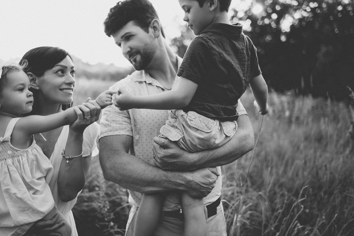 Black and white candid photo of a family sharing joyful moments together outdoors.