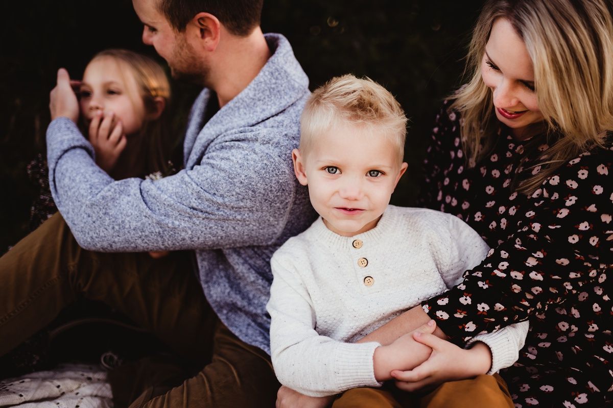 A candid family portrait showing genuine emotions and laughter outdoors.