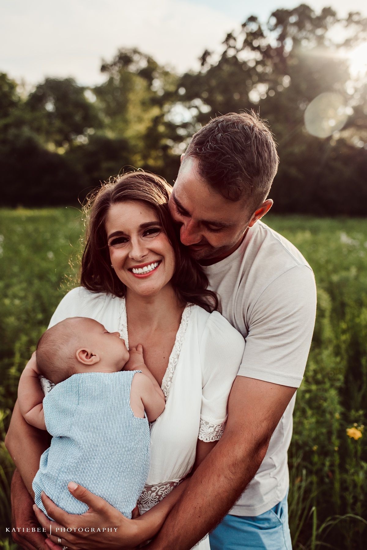 Happy family with infant enjoying golden hour in a meadow setting.