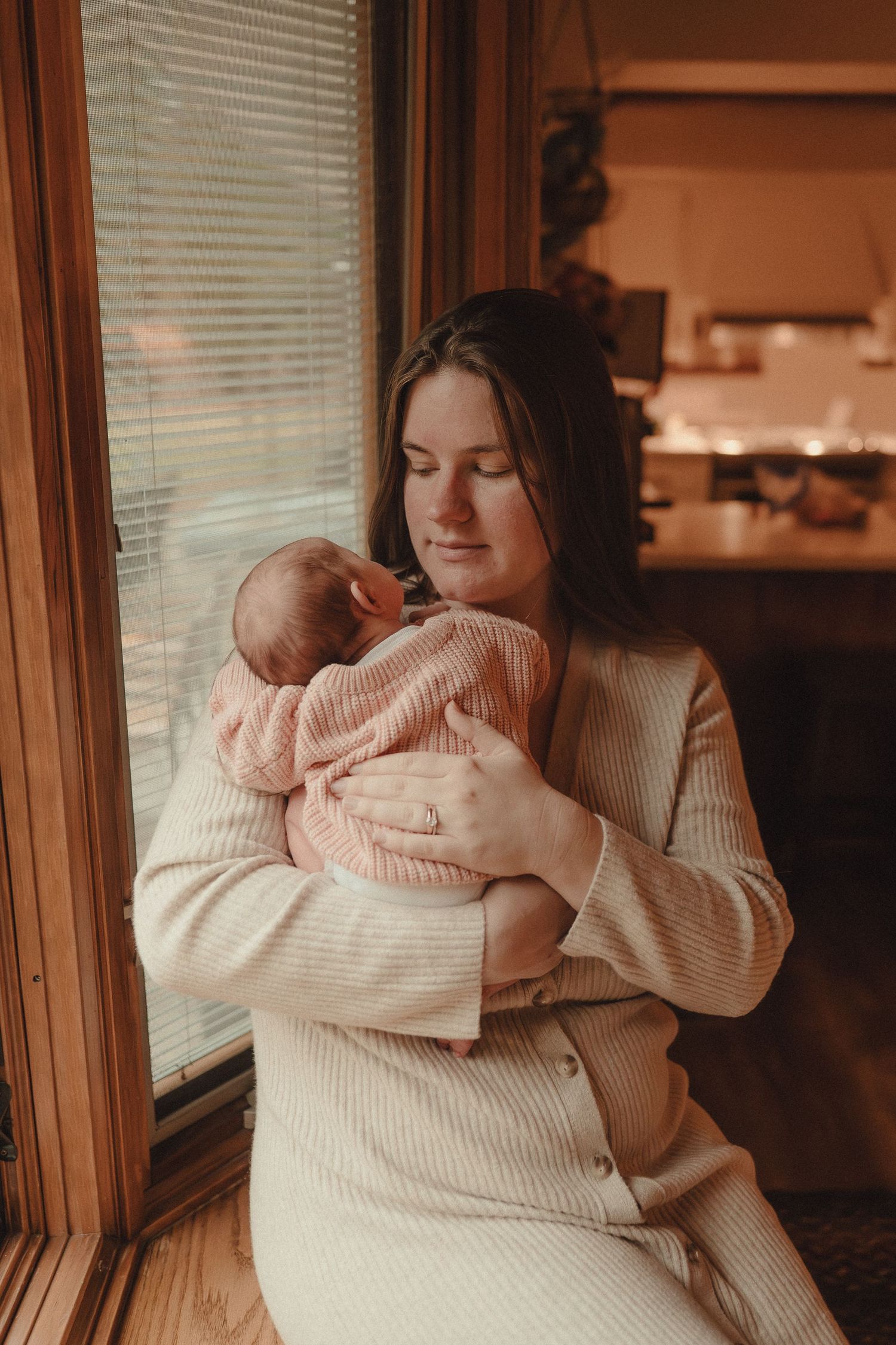 Gentle candid moments between parent and baby captured in warm, natural lighting.